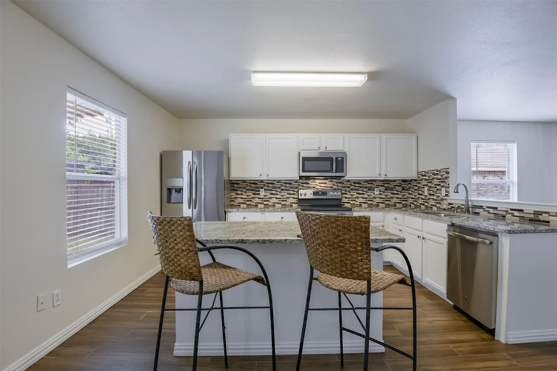 Modern kitchen featuring an island with space for seating, granite countertops.