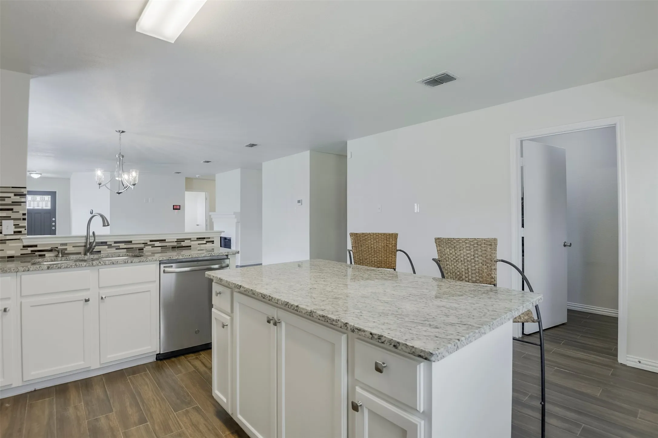 Kitchen featuring an island with granite countertops and white cabinetry.