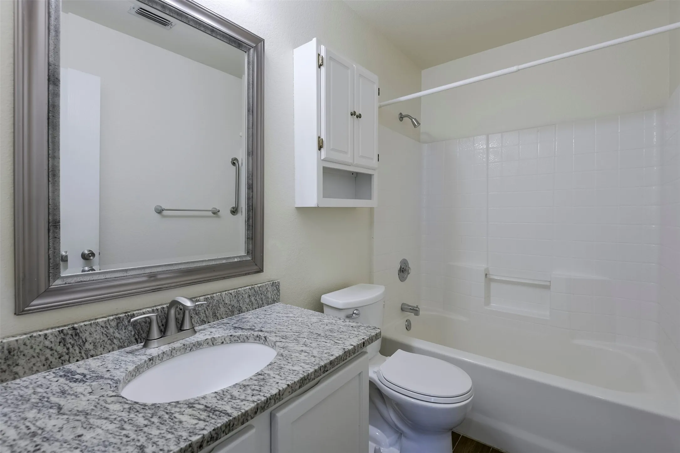 Bathroom vanity with a granite countertop, undermount sink, and brushed nickel faucet