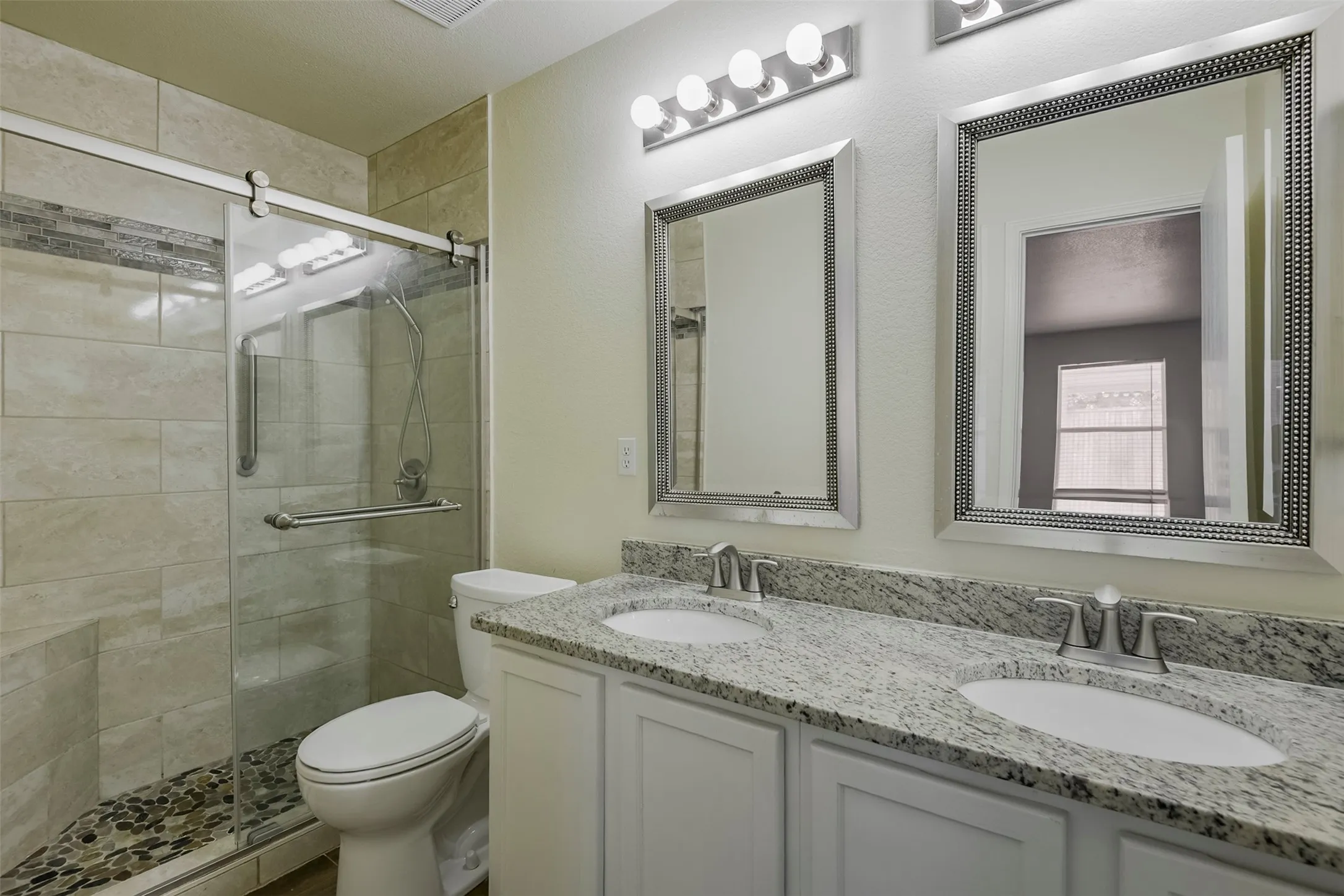 Dual vanity with granite countertops, undermount sinks, and framed mirrors