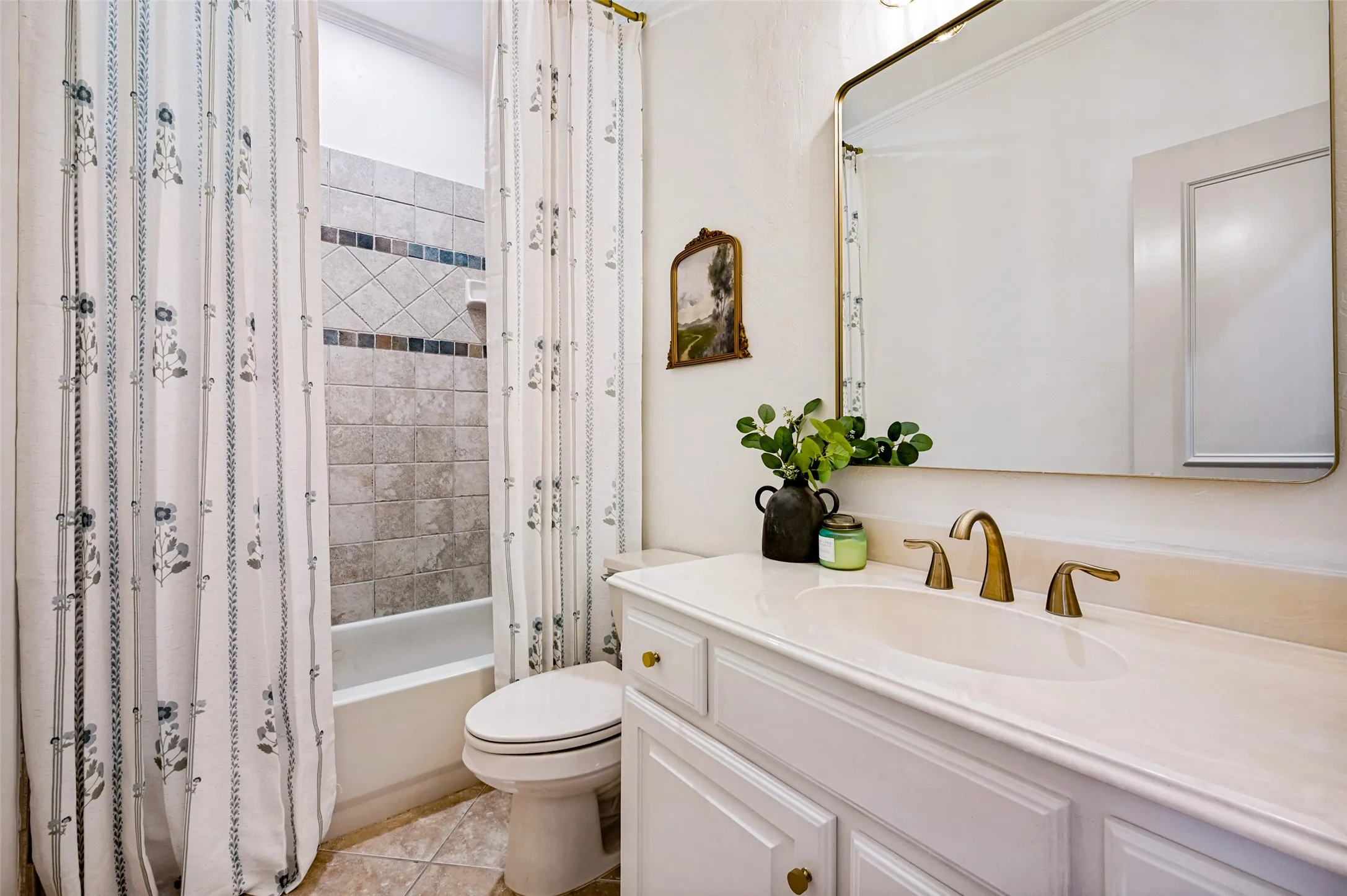 Bathroom featuring a vanity with an integrated sink, polished brass-finish faucet, and a wall-mounted mirror