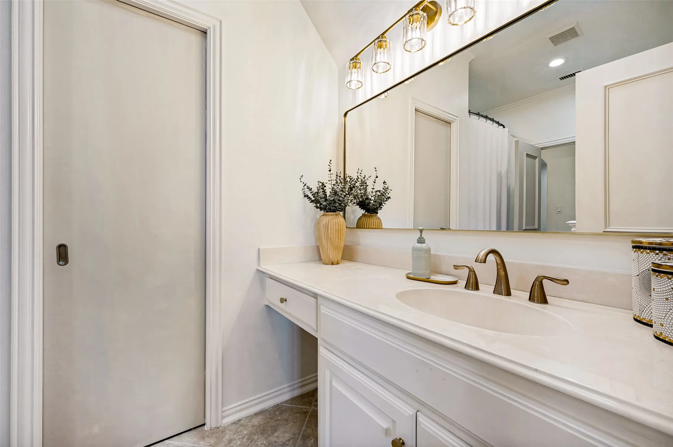 White vanity with an integrated basin, bronze-finish faucet, and a large wall-mounted mirror