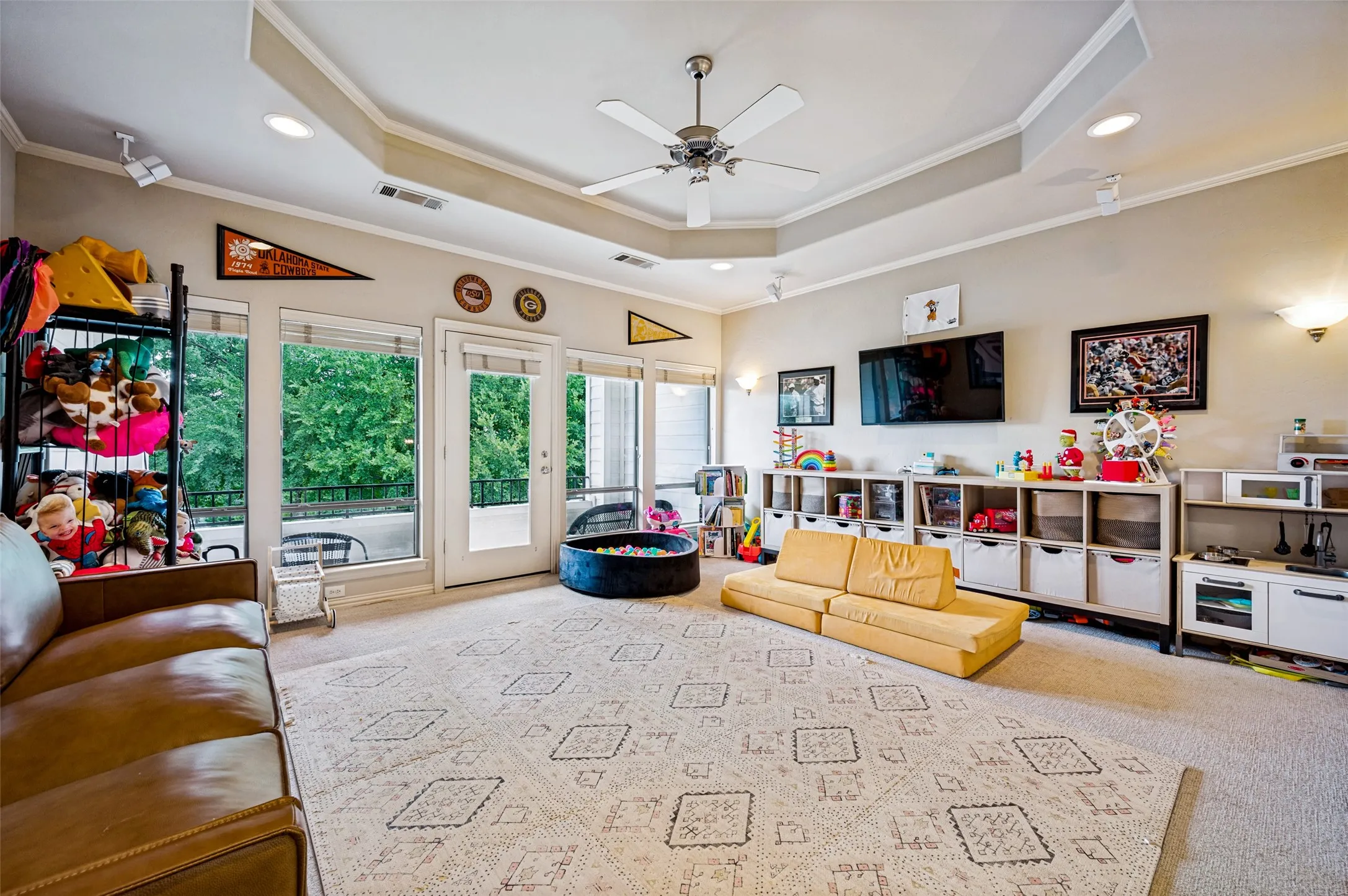 Tray ceiling with recessed lighting, ceiling fan, multiple windows, and a glass-paneled door