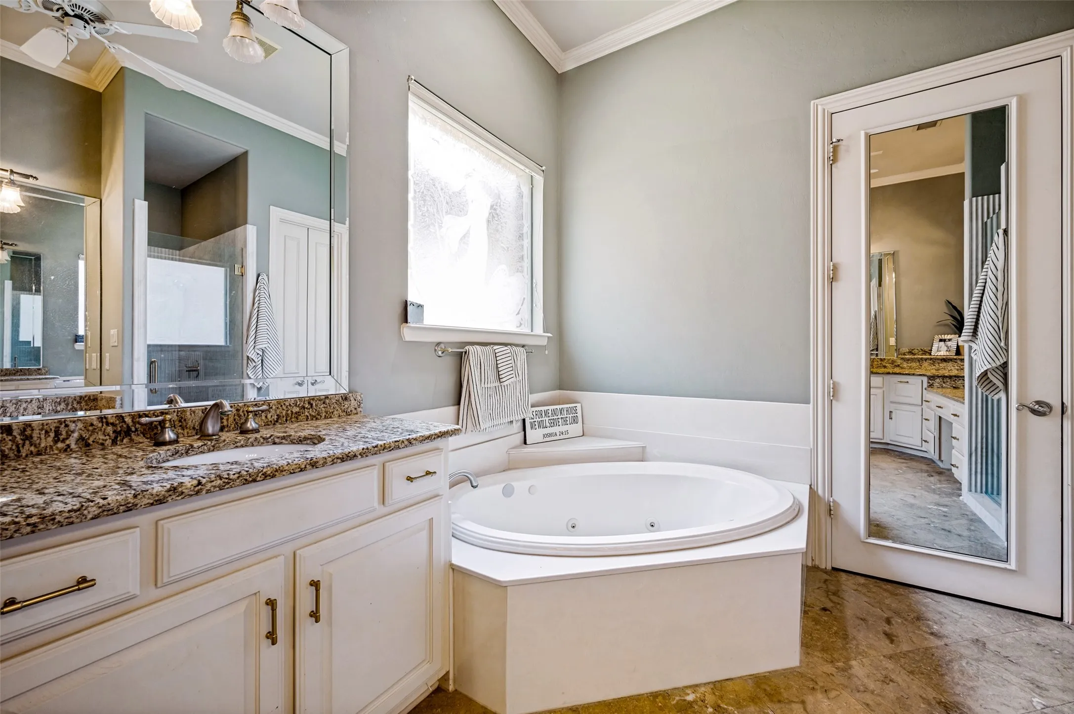 Built-in soaking tub, dual vanity with stone countertop, tile flooring, and vaulted ceiling