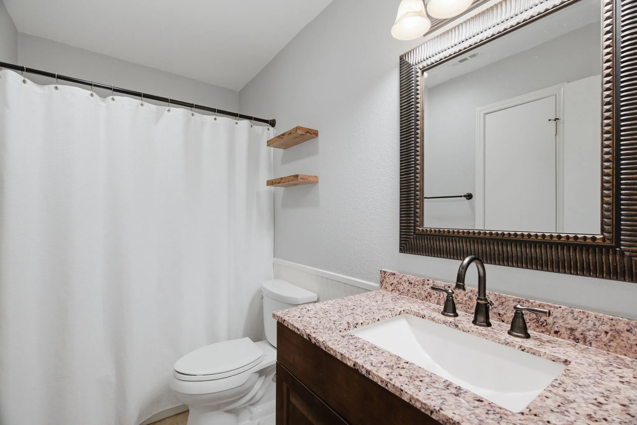 Bathroom vanity featuring a speckled countertop, undermount sink, and dark bronze faucet