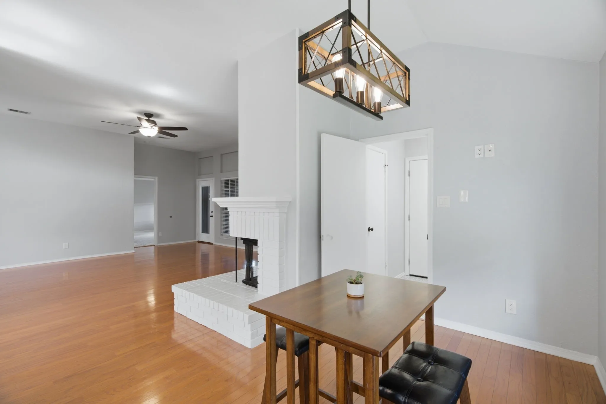 Spacious living area featuring light wood-finish flooring and a white brick fireplace