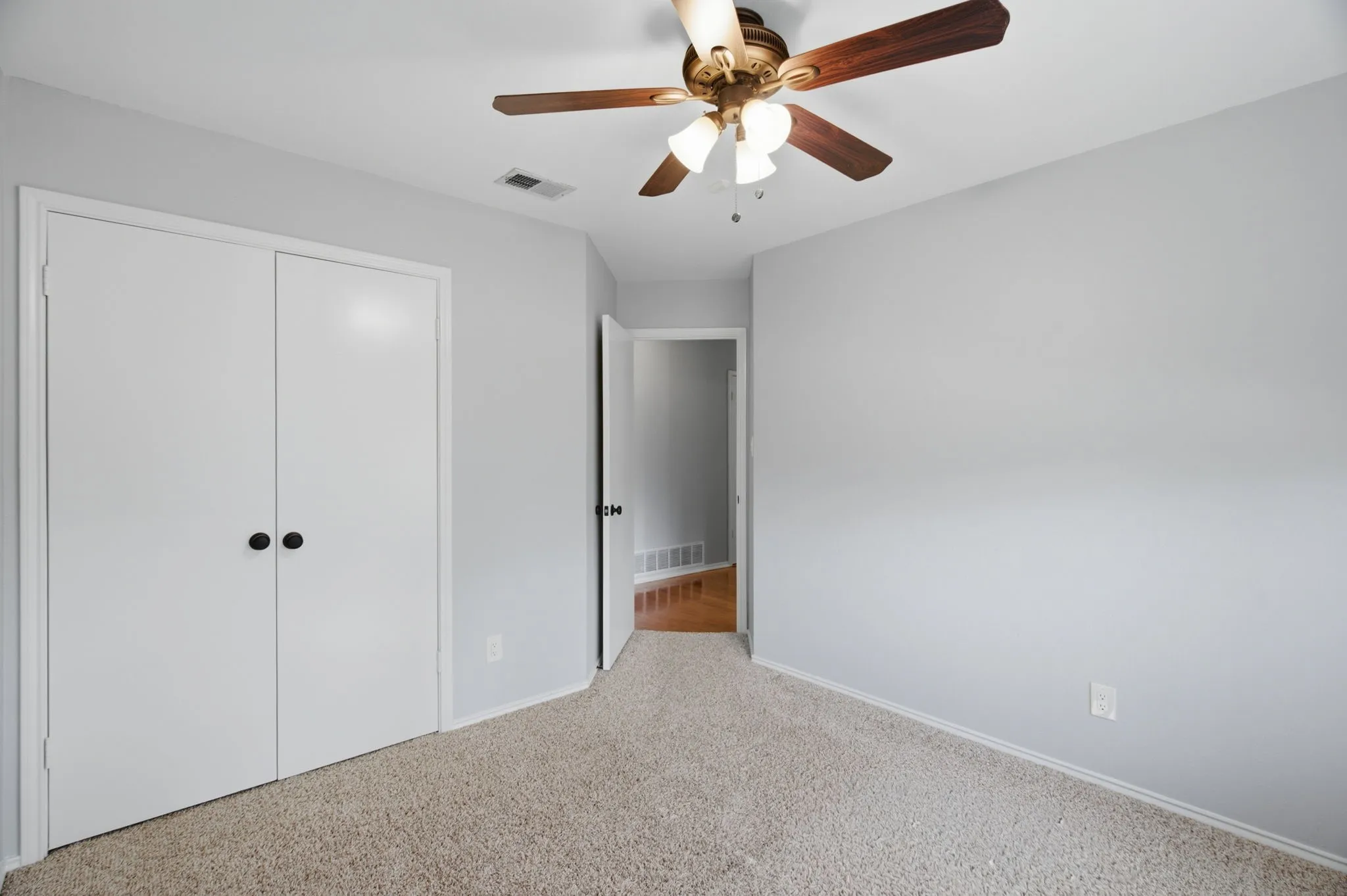 Bedroom featuring light gray walls, textured carpeting, and a ceiling fan with light fixture