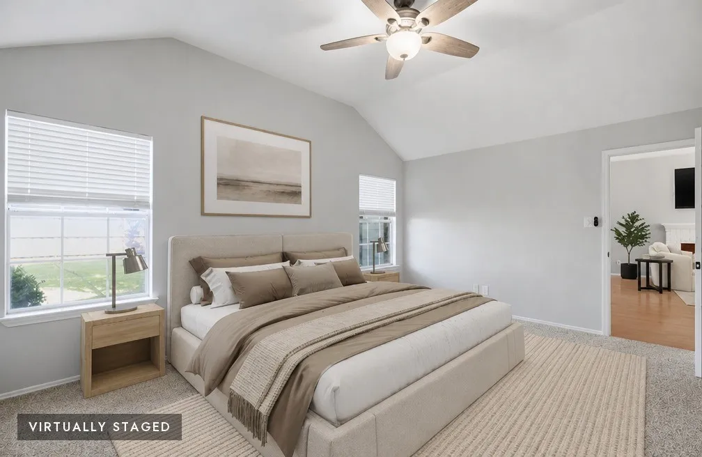 Spacious bedroom featuring vaulted ceilings, a ceiling fan with integrated lighting, two windows with blinds, and light-toned carpet flooring, virtually staged