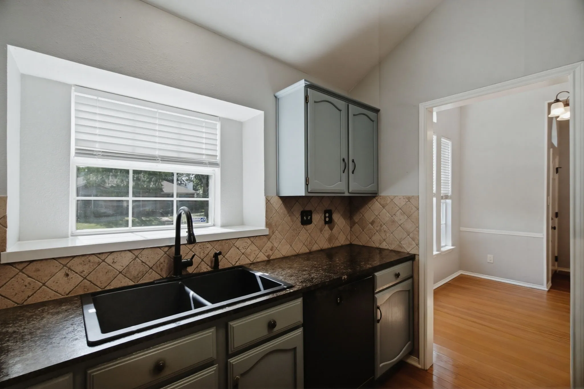 Kitchen featuring a double basin sink with a matte black faucet, dark countertops, and a diamond-patterned tile backsplash
