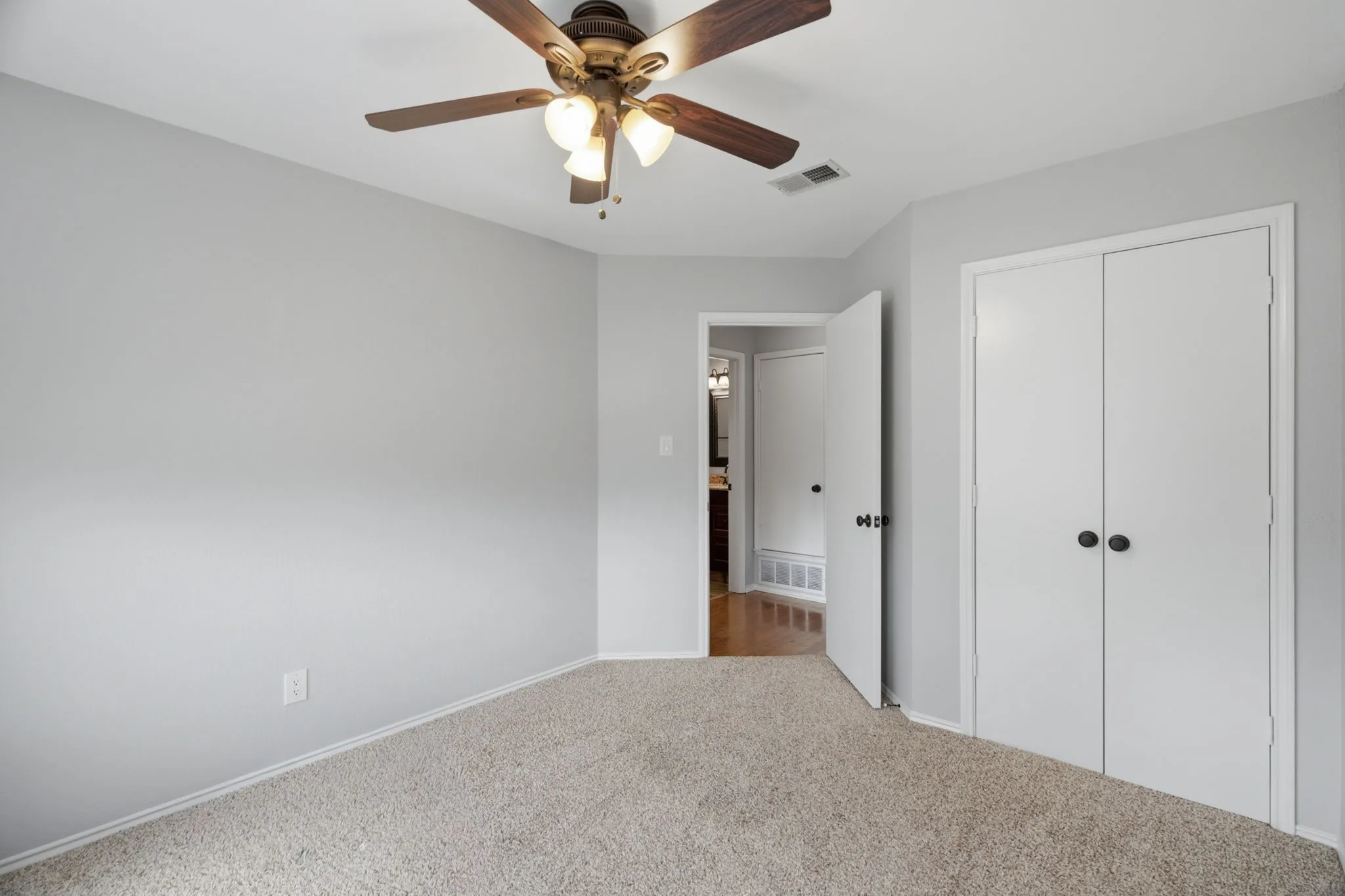 Bedroom featuring light gray walls, neutral carpet, and a ceiling fan with light fixture