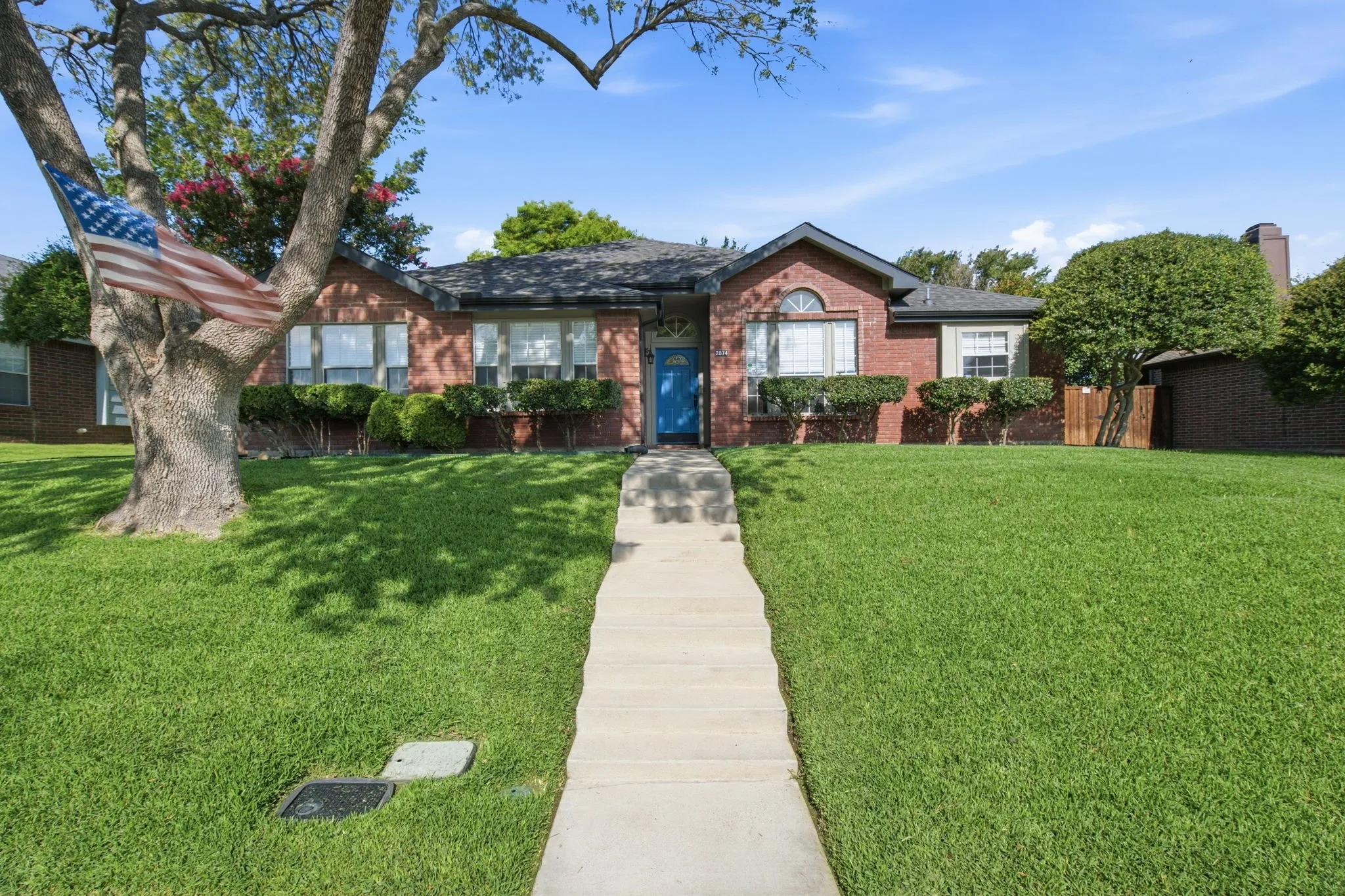 Brick-clad facade featuring a vibrant blue entry door, an arched window, and a dark roofline