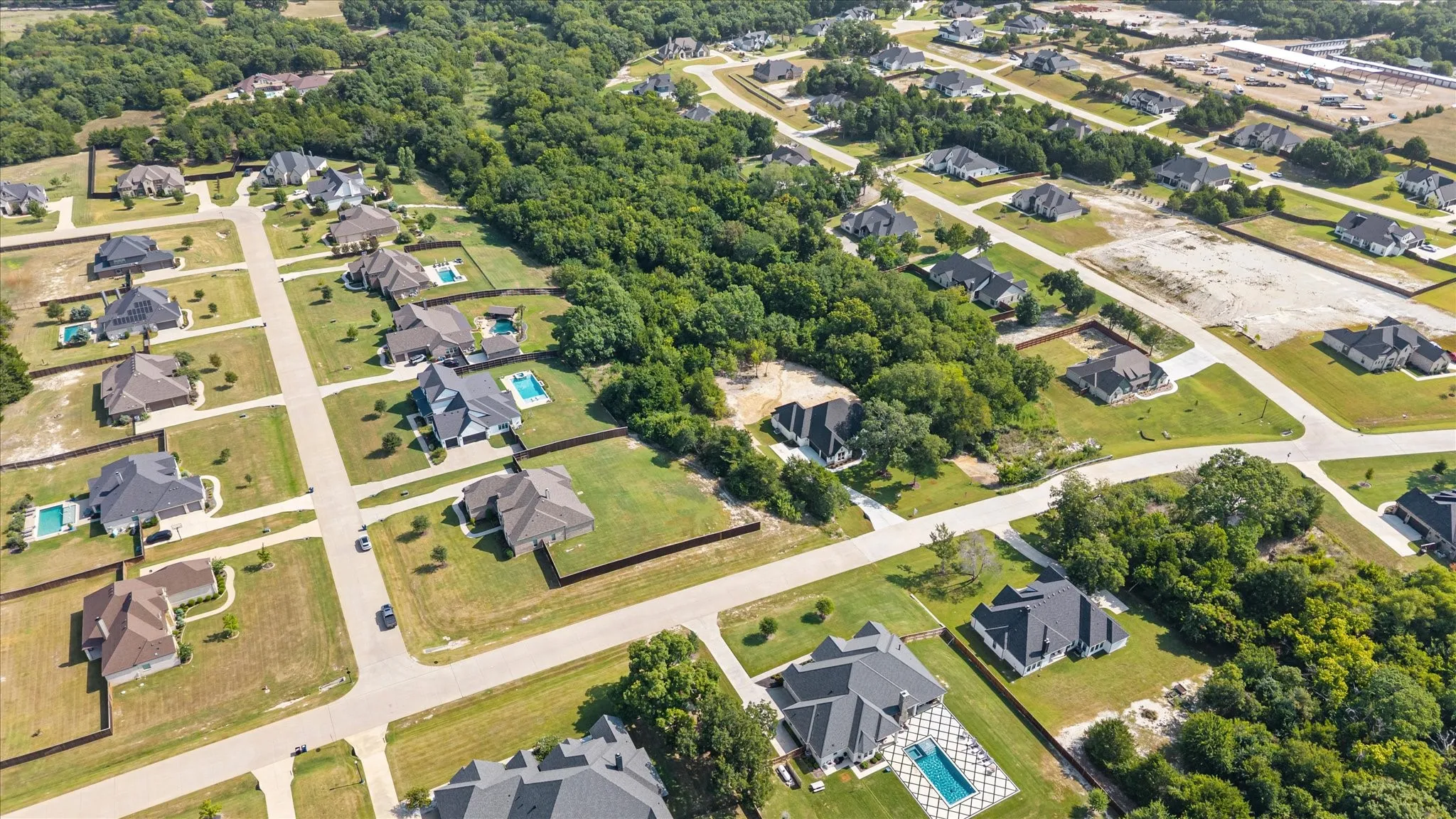 Residential community with established homes, green spaces, paved roadways, and private swimming pools