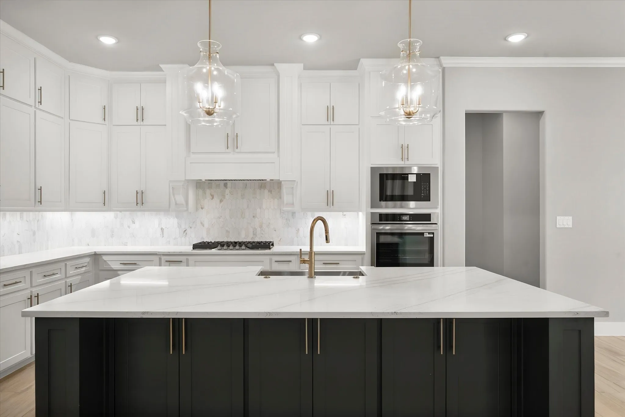 Modern kitchen featuring white cabinetry with brushed nickel hardware, quartz countertops, and a striking black island with waterfall edge