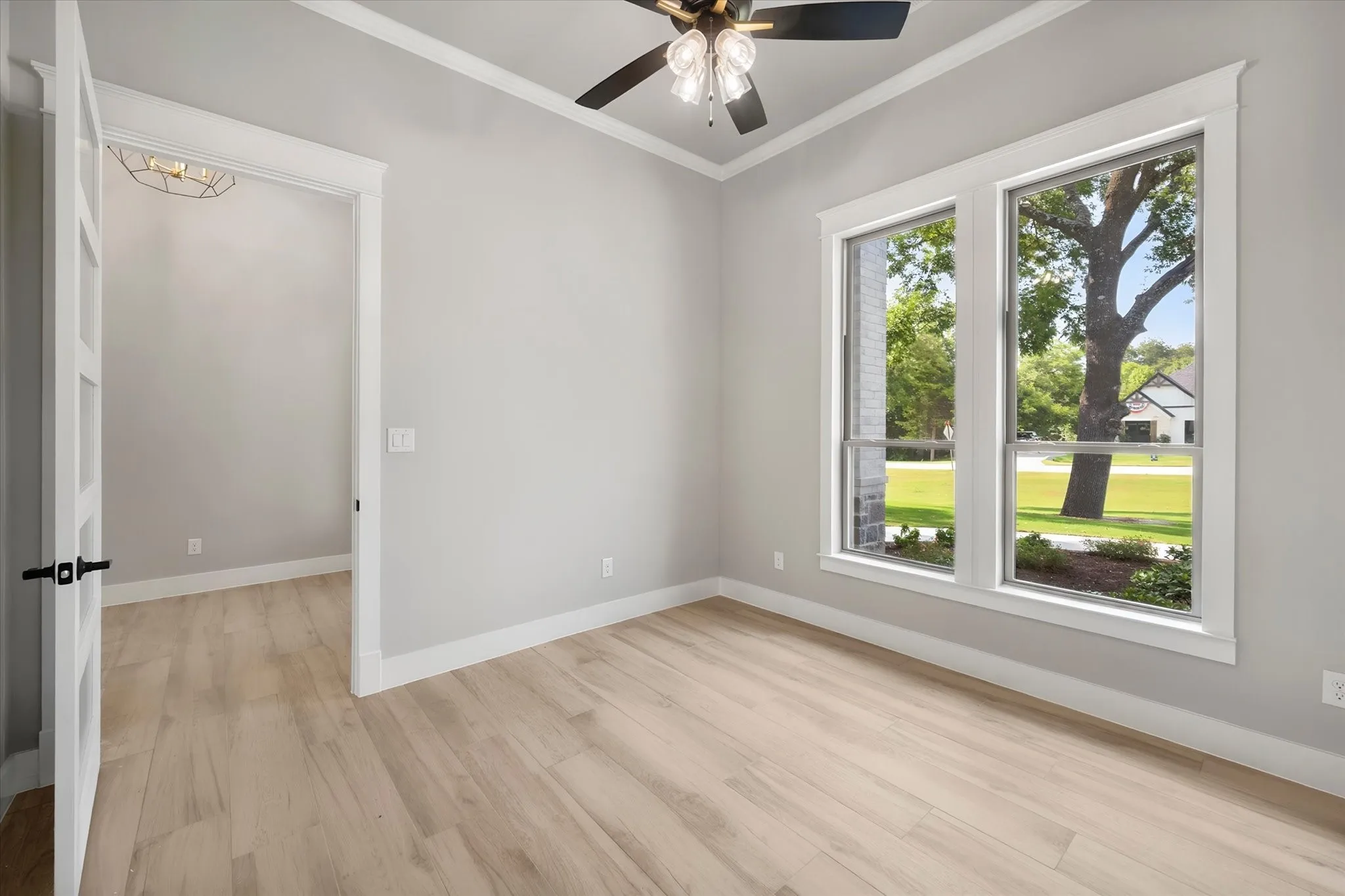 Light wood-finish flooring, dual windows, and ceiling fan with integrated lighting