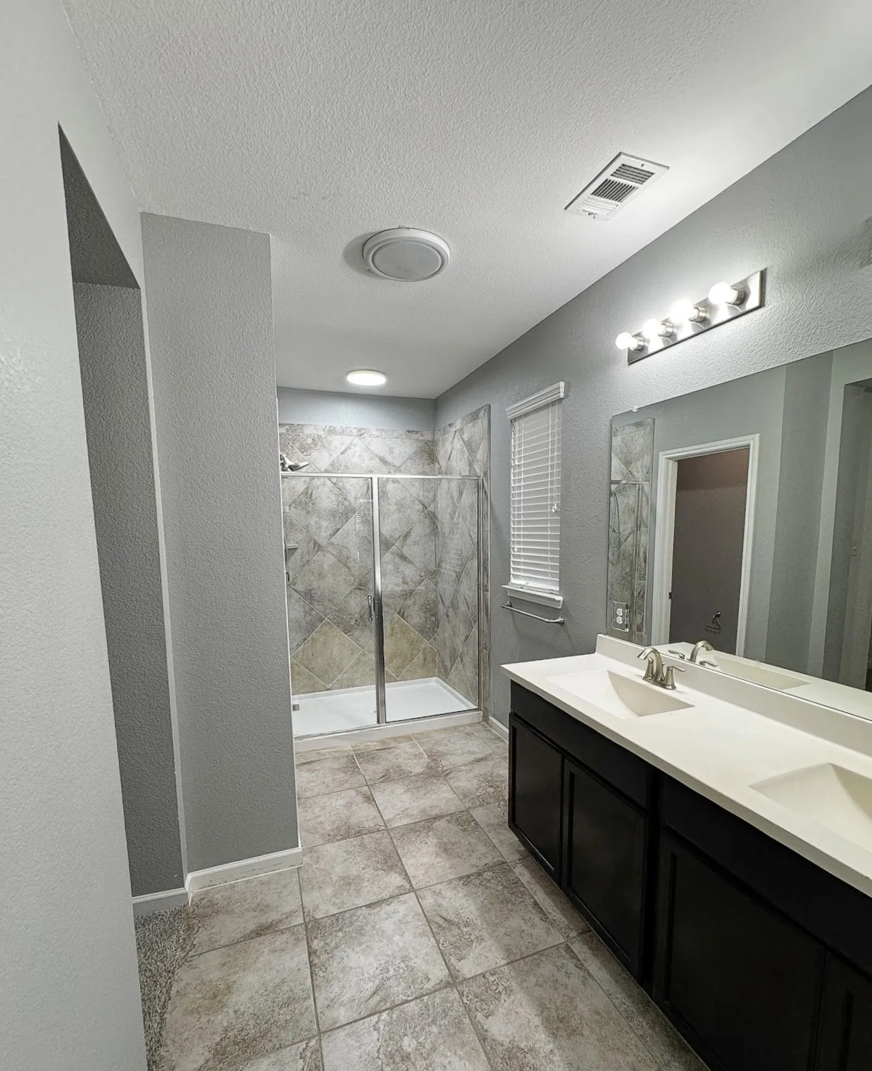 Dual vanity with integrated sinks, a framed mirror, and a multi-bulb light fixture