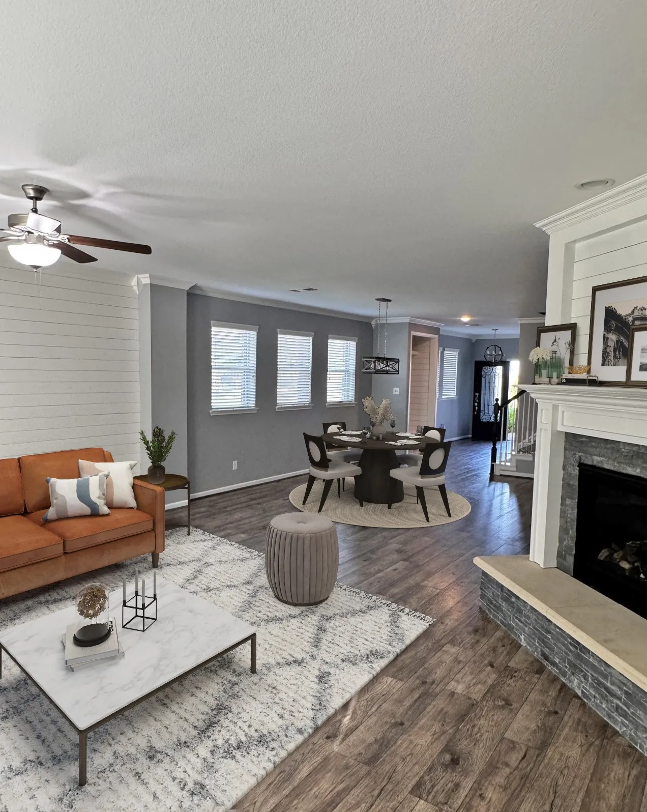 Open concept living and dining areas featuring wood-finish flooring, a built-in fireplace with a stone surround, and multiple windows