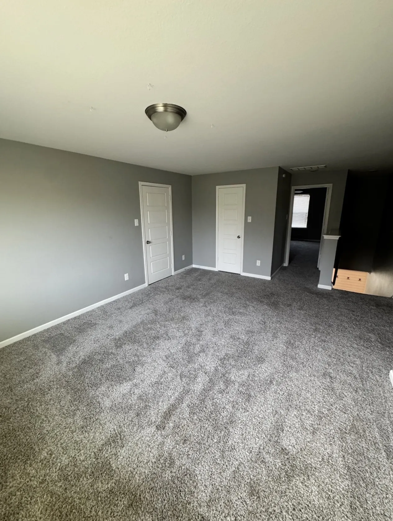 Plush grey carpeting, neutral wall color, white trim, and a semi-flush ceiling light fixture