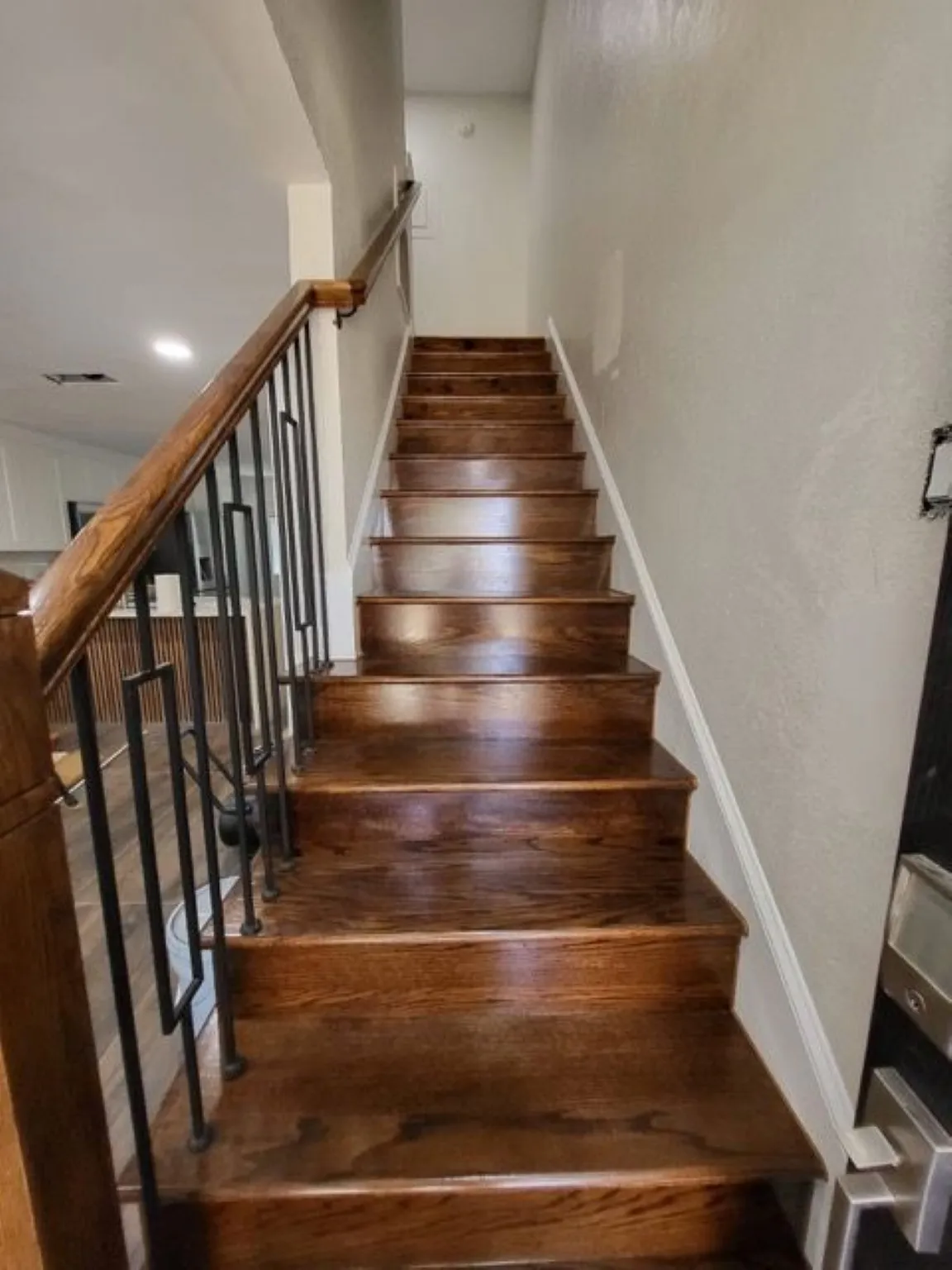 Rich wood-finish staircase with contemporary black metal balusters and a coordinating wood handrail