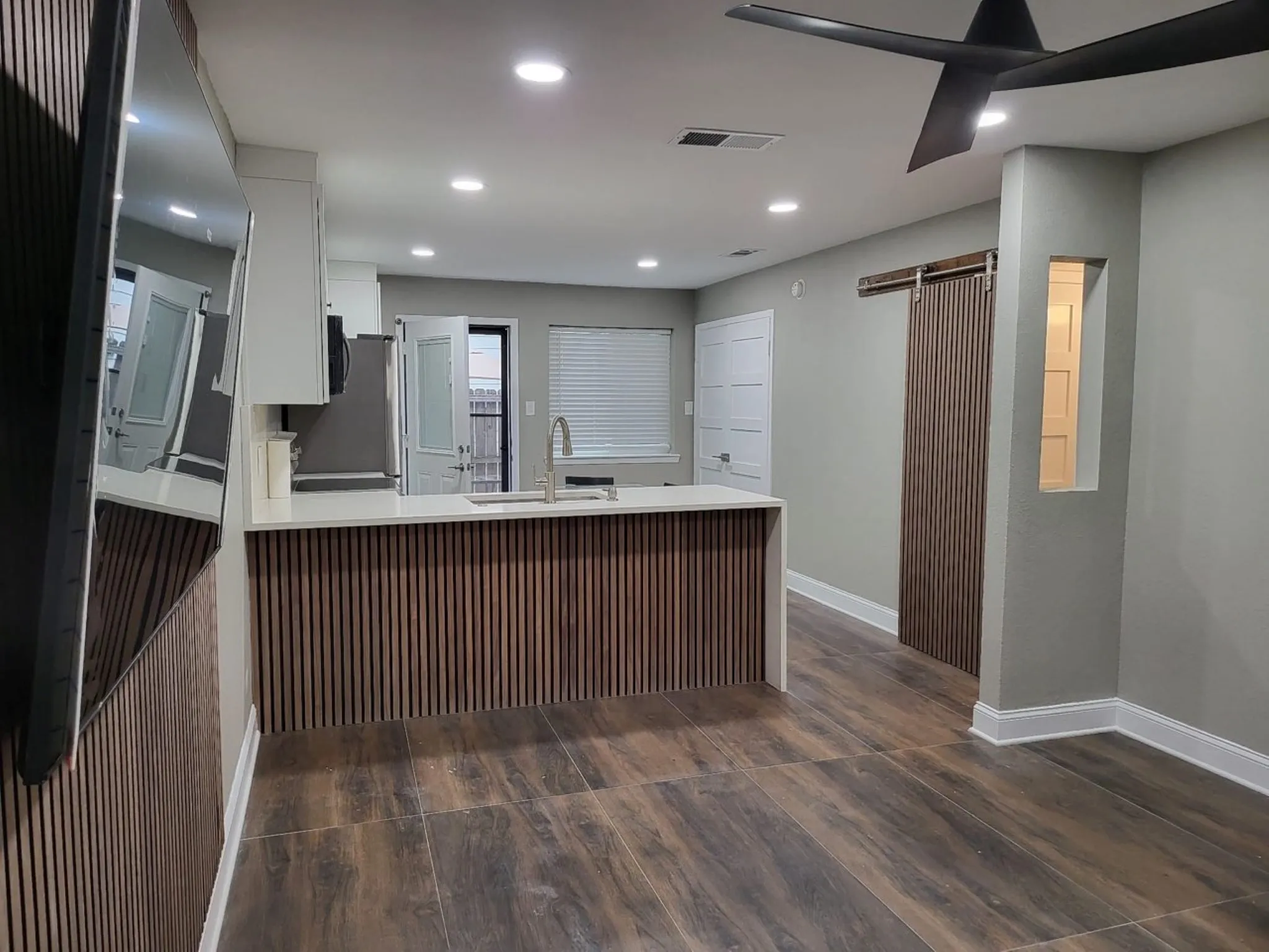 Open-concept living area with wood-finish flooring, recessed lighting, and a modern ceiling fan