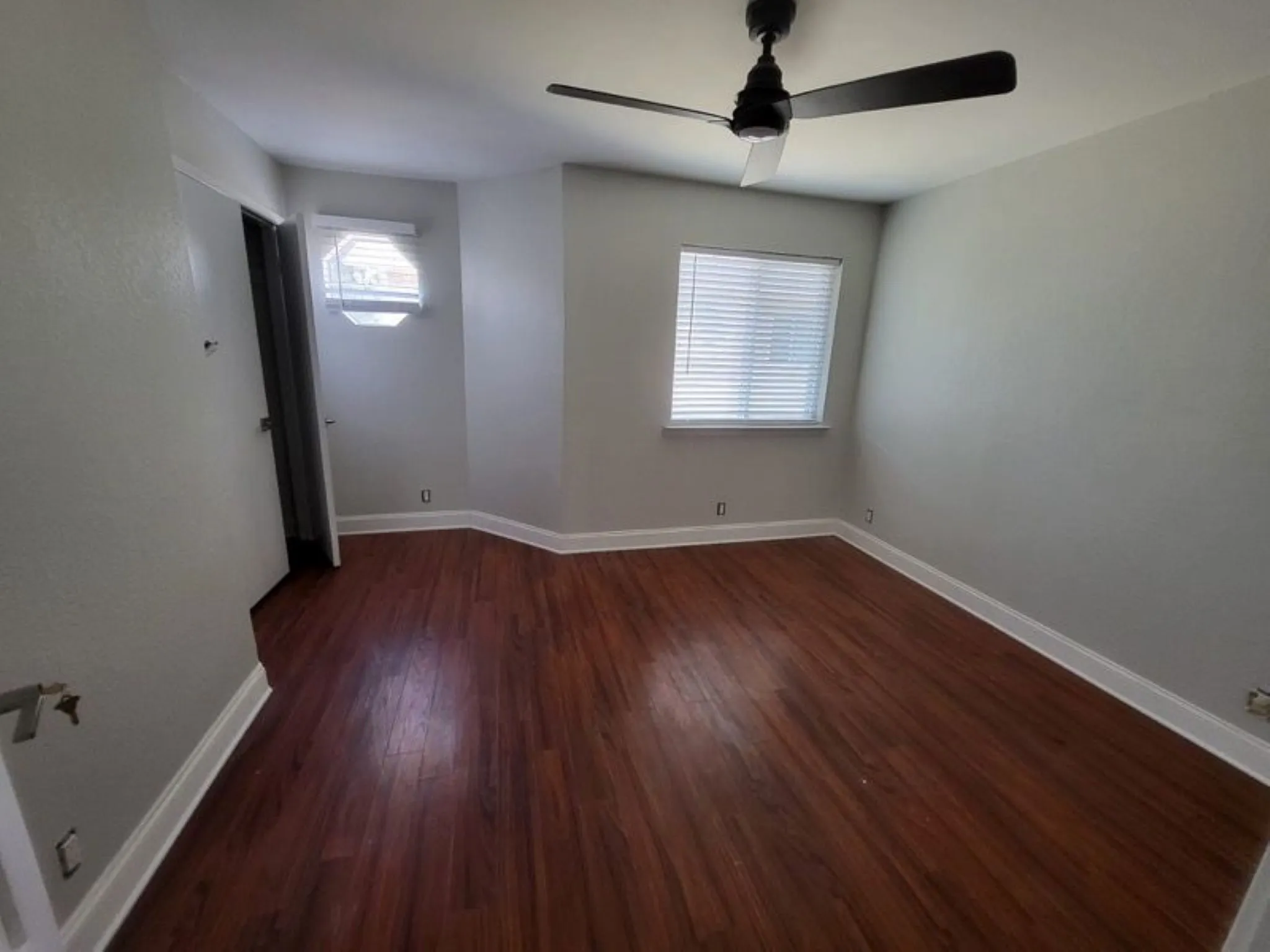Interior room featuring wood-finish flooring, light gray wall paint, and white baseboards