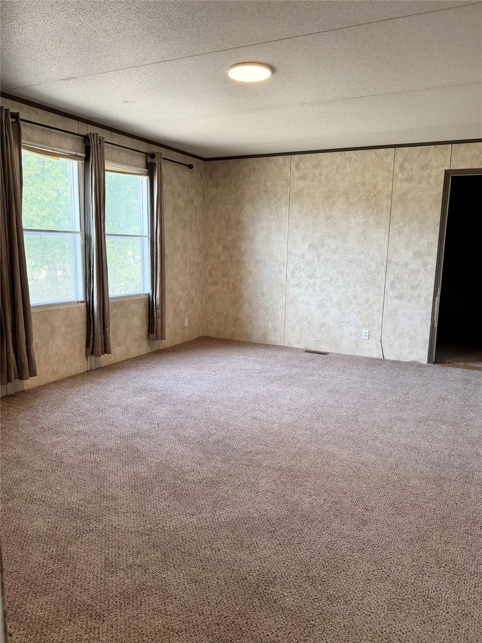 Carpeted interior space with three windows providing natural illumination