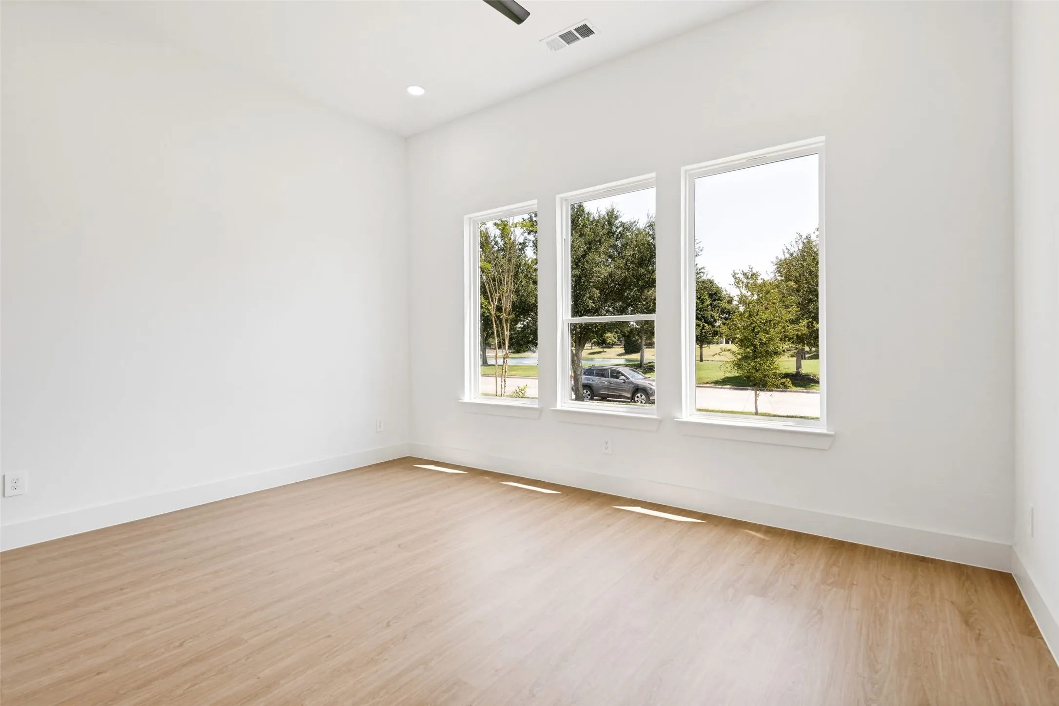 Spacious room with light wood-finish flooring, white walls, and bright white trim