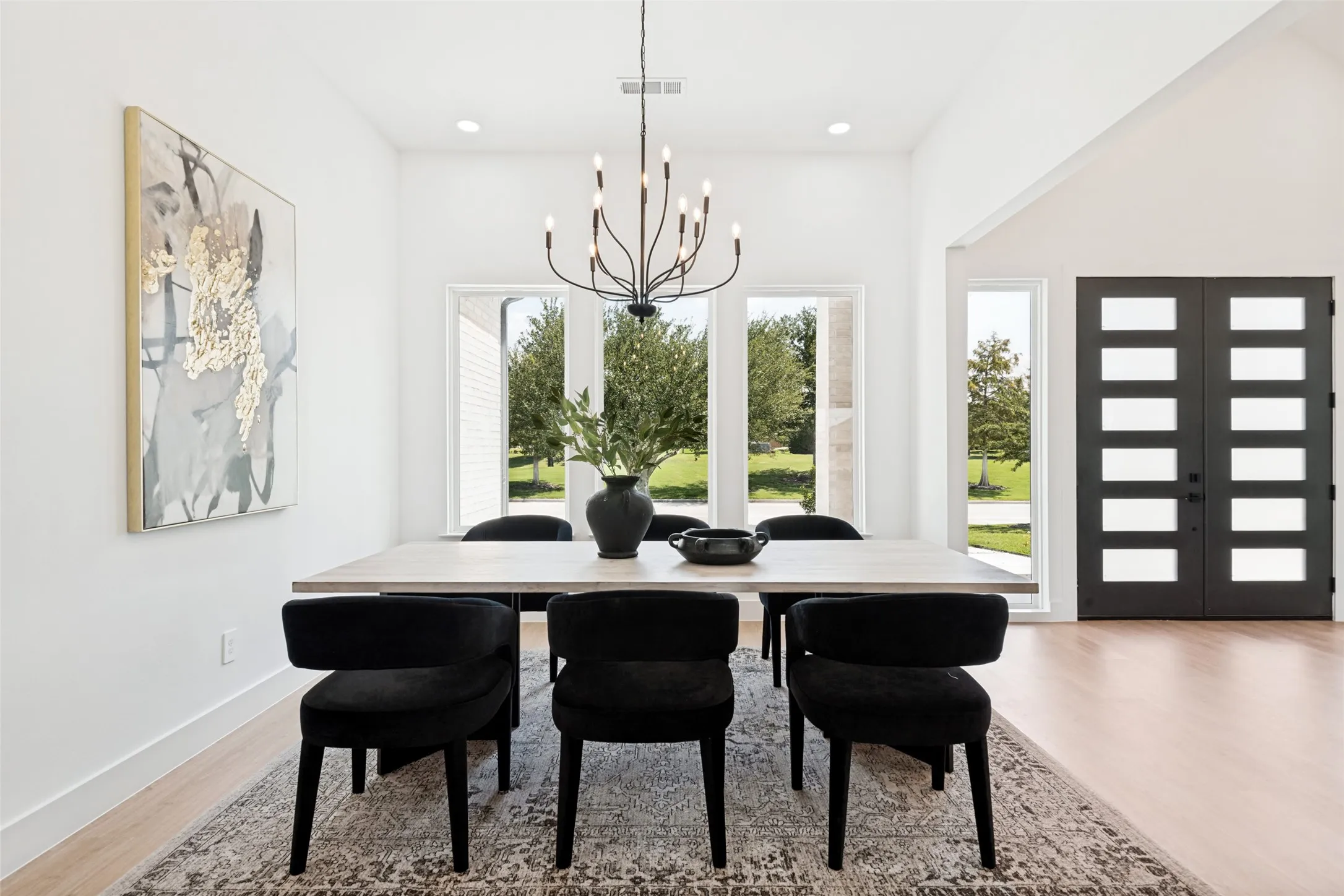 Dining area featuring vaulted ceilings, light wood-finish flooring, and a contemporary chandelier