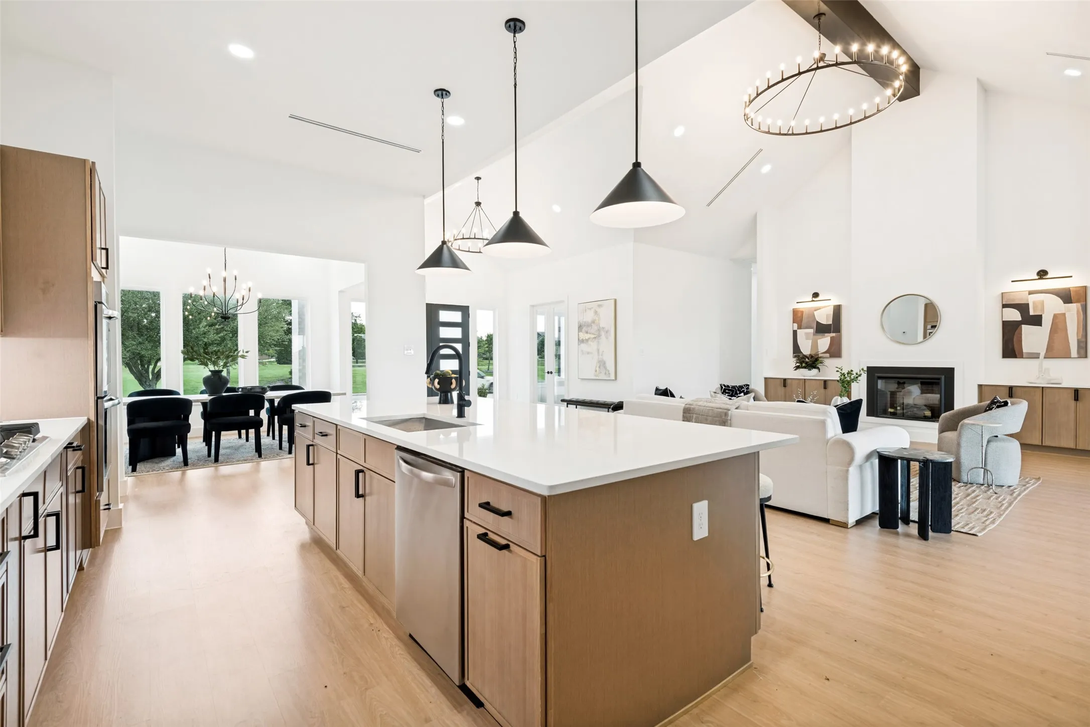 Open-concept living area featuring a kitchen island with integrated sink, stainless steel appliances, and wood-finish flooring