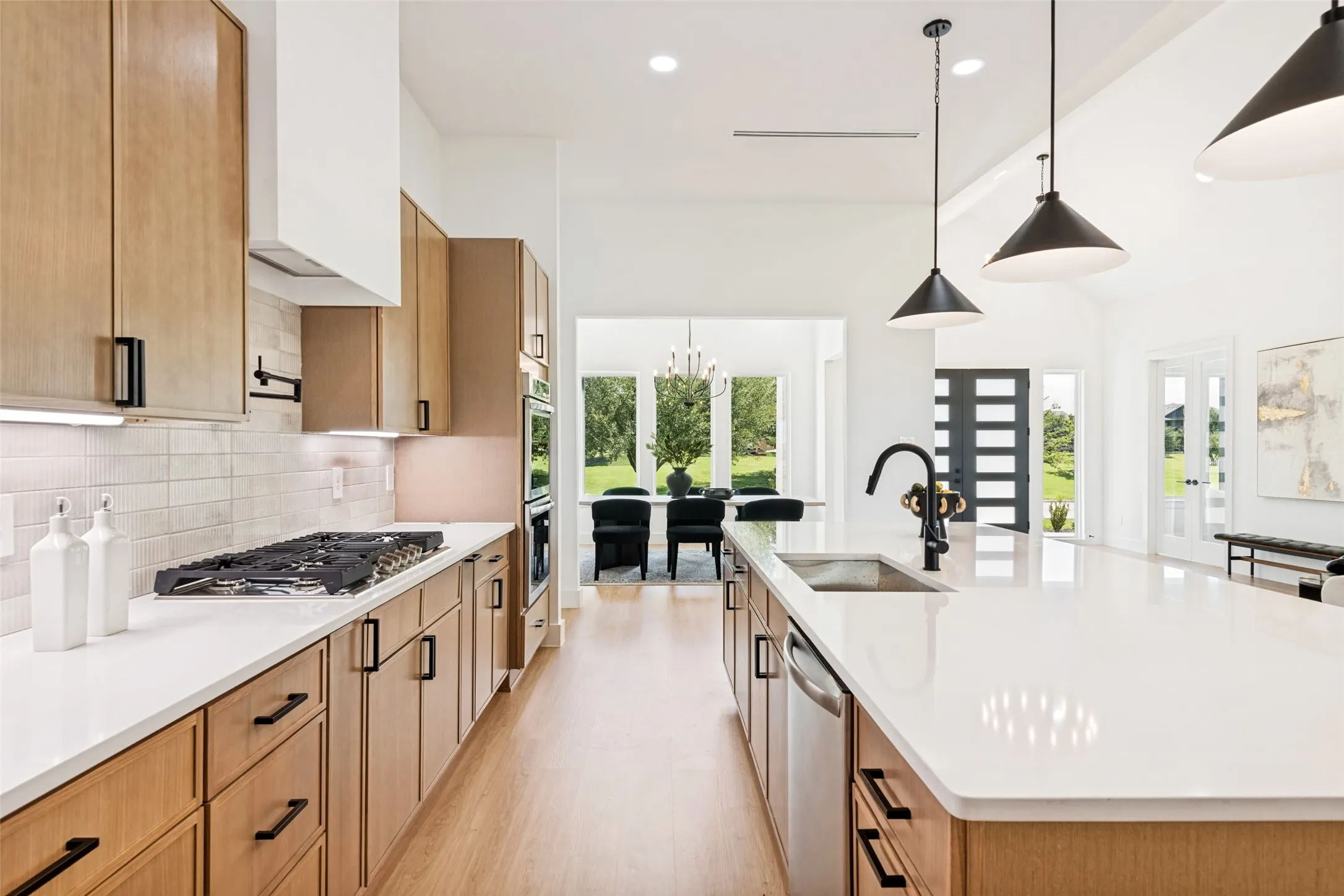 Modern kitchen featuring wood-finish cabinetry, white countertops, and a tile backsplash