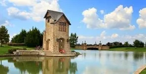 Stone tower structure with arched openings, situated at the edge of a water feature