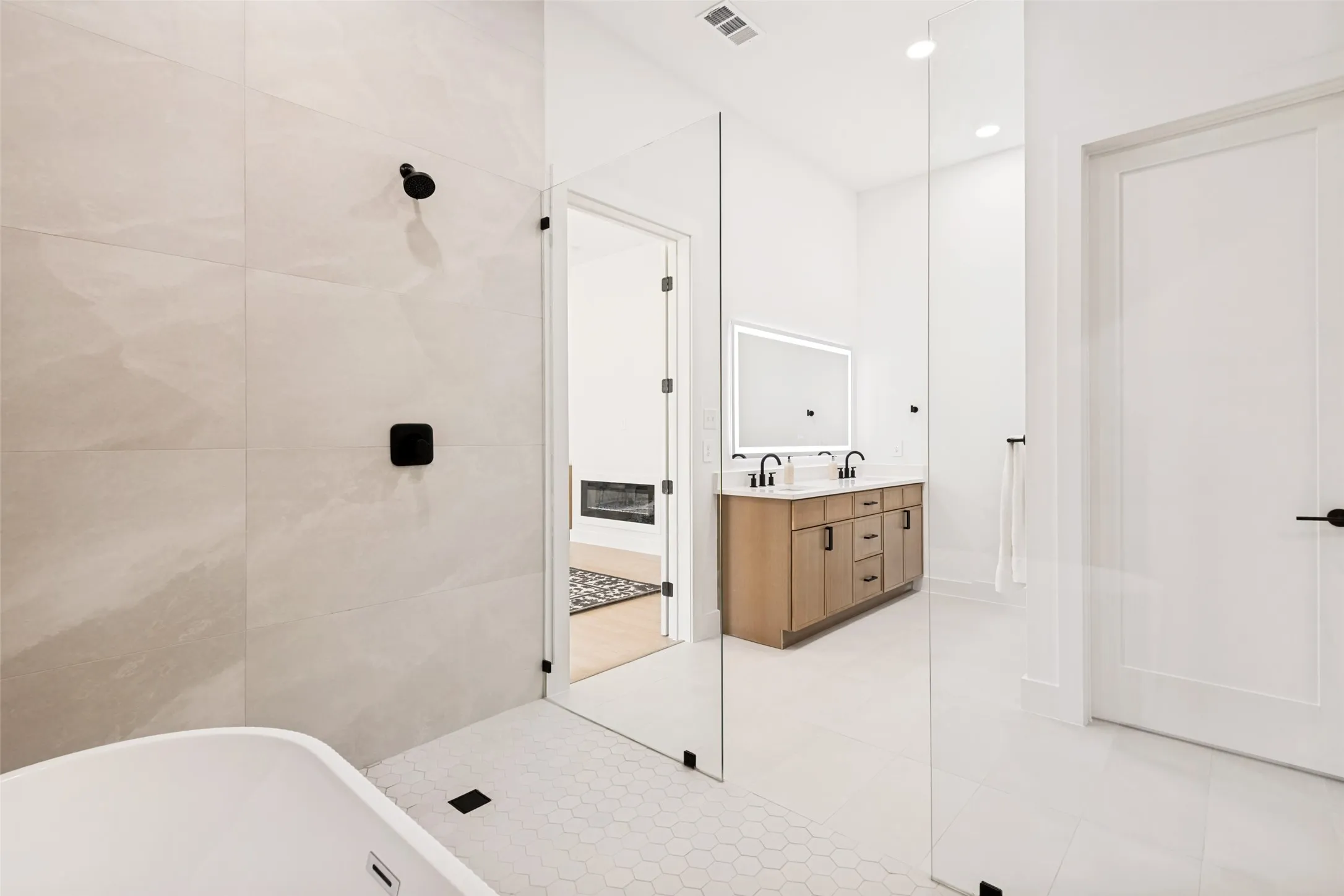 Contemporary bathroom featuring a freestanding tub, glass-enclosed shower with large format tile, dual vanity with undermount sinks, and matte black fixtures