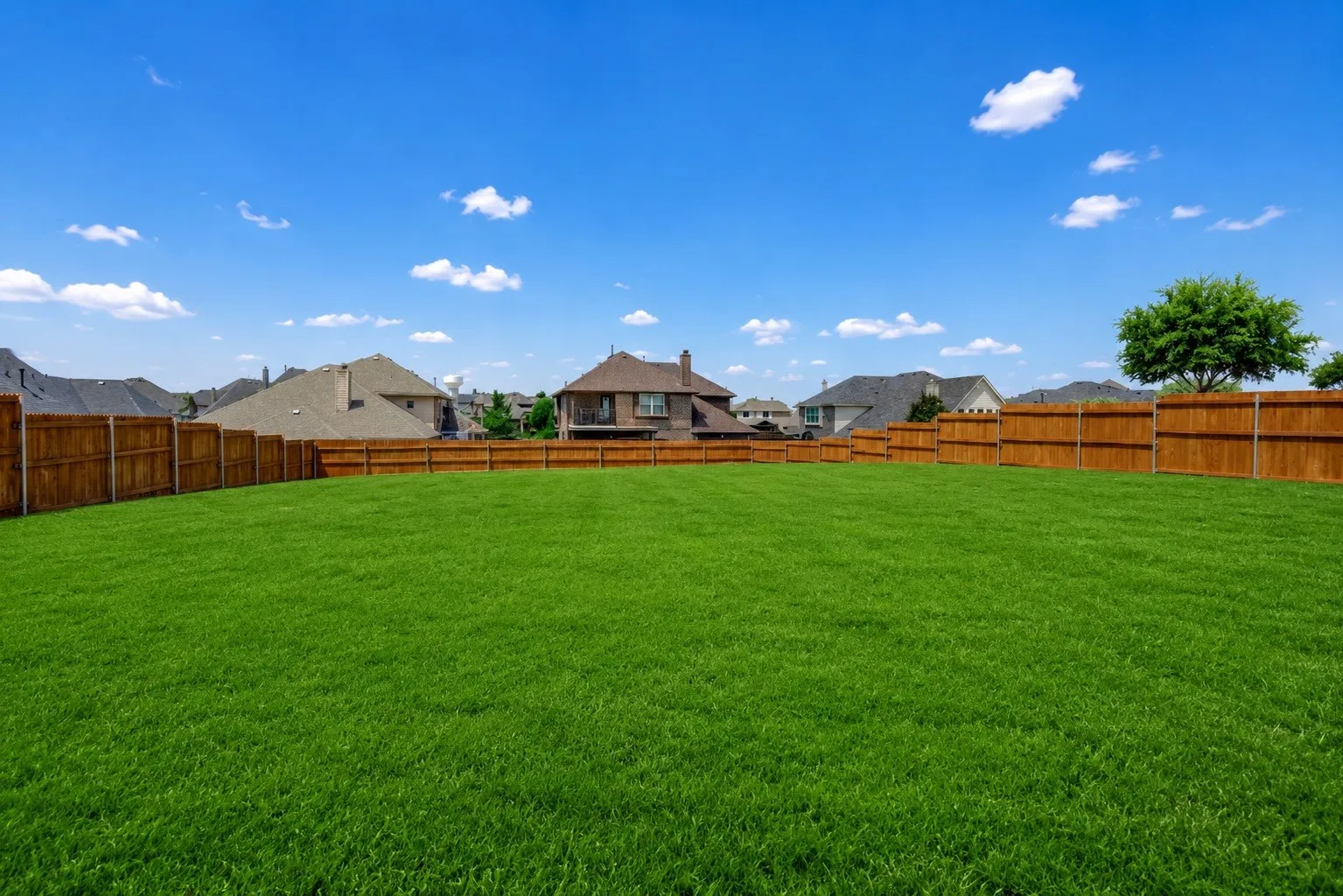 Expansive green lawn fully enclosed by a wood privacy fence