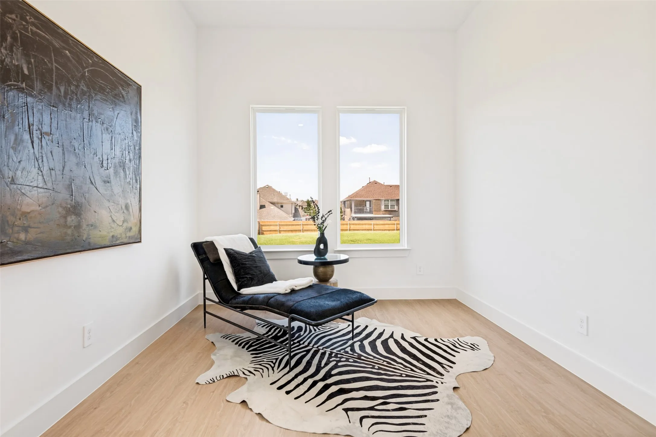 Bright room featuring light wood-finish flooring, white walls, and a large window with a white frame