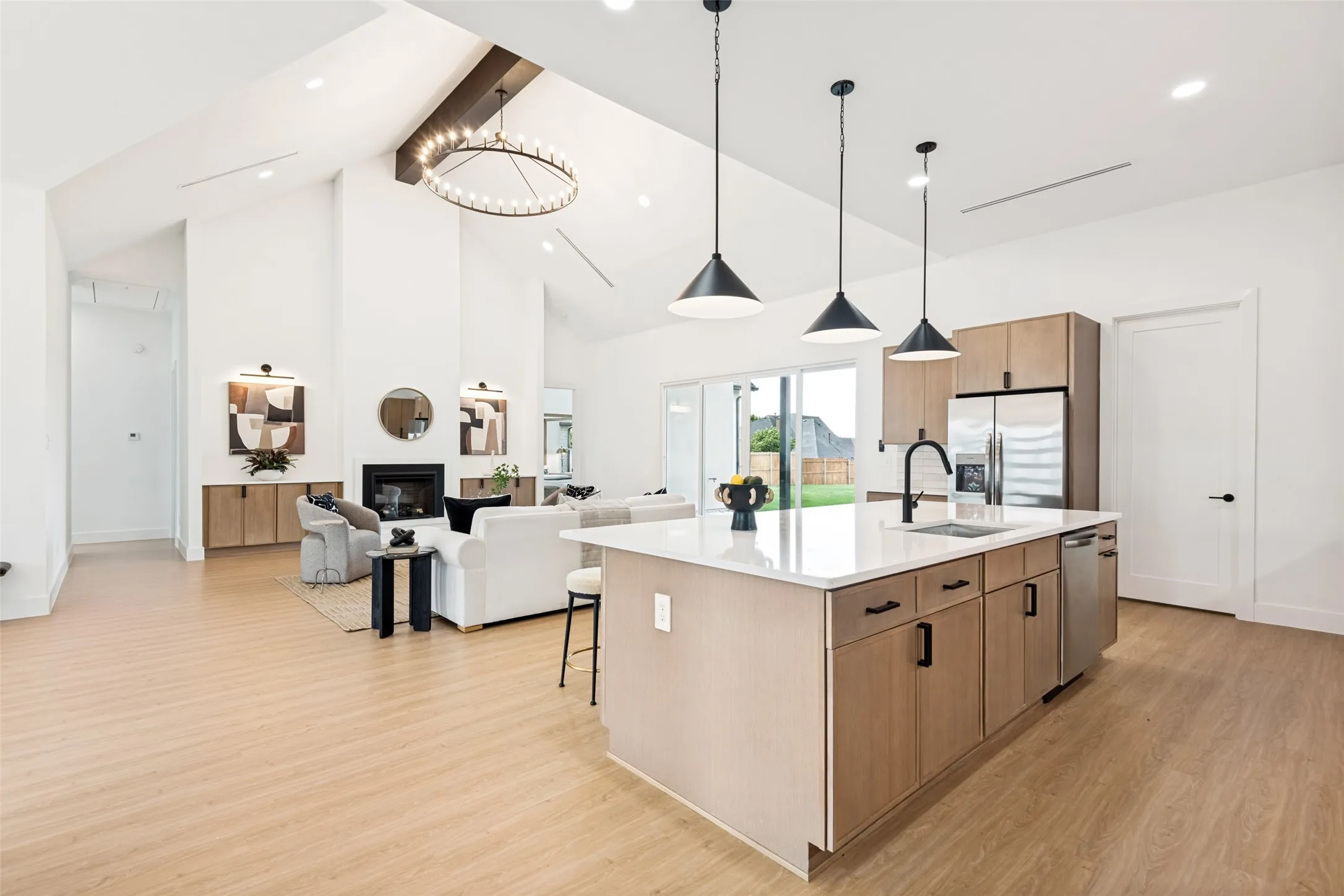 Open-concept living space featuring a central kitchen island with seating, integrated appliances, and pendant lighting