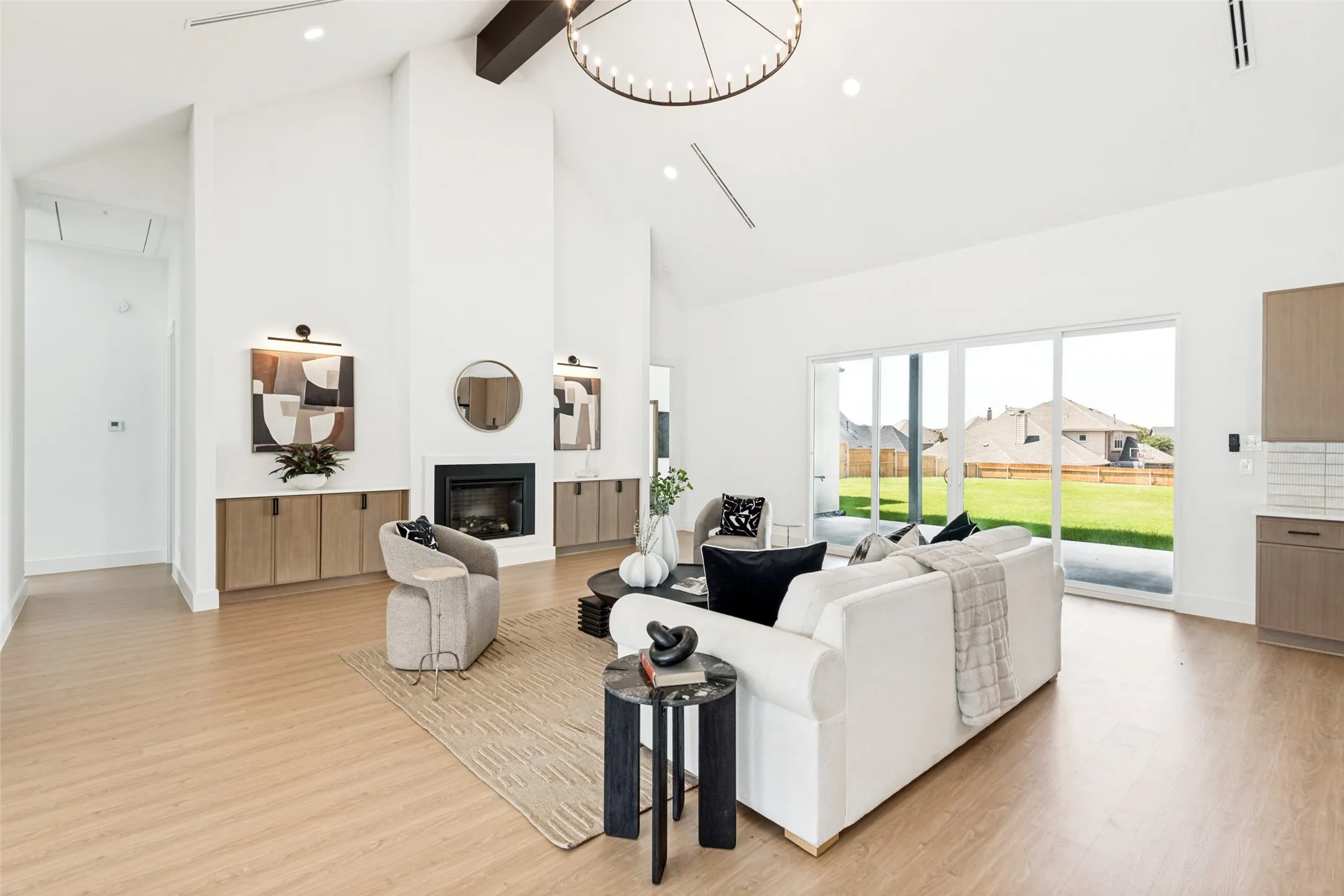 Vaulted ceiling living area featuring a fireplace, built-in cabinetry, wood-finish flooring, and large sliding glass doors