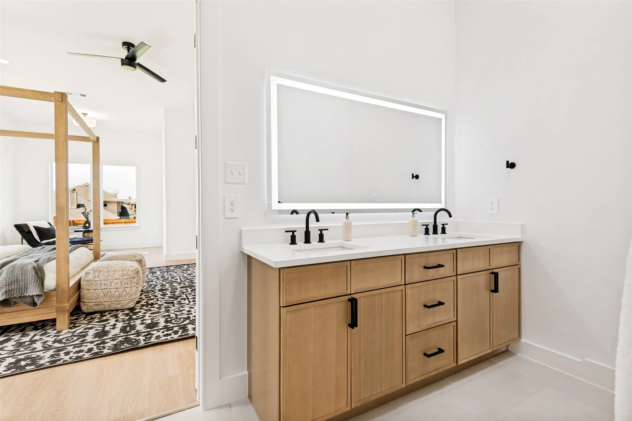Double vanity with a lighted mirror, two undermount sinks, and matte black fixtures