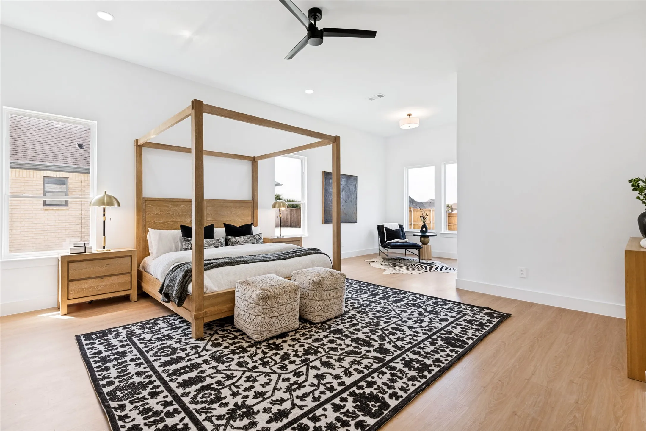 Spacious bedroom featuring light wood-finish flooring and multiple windows