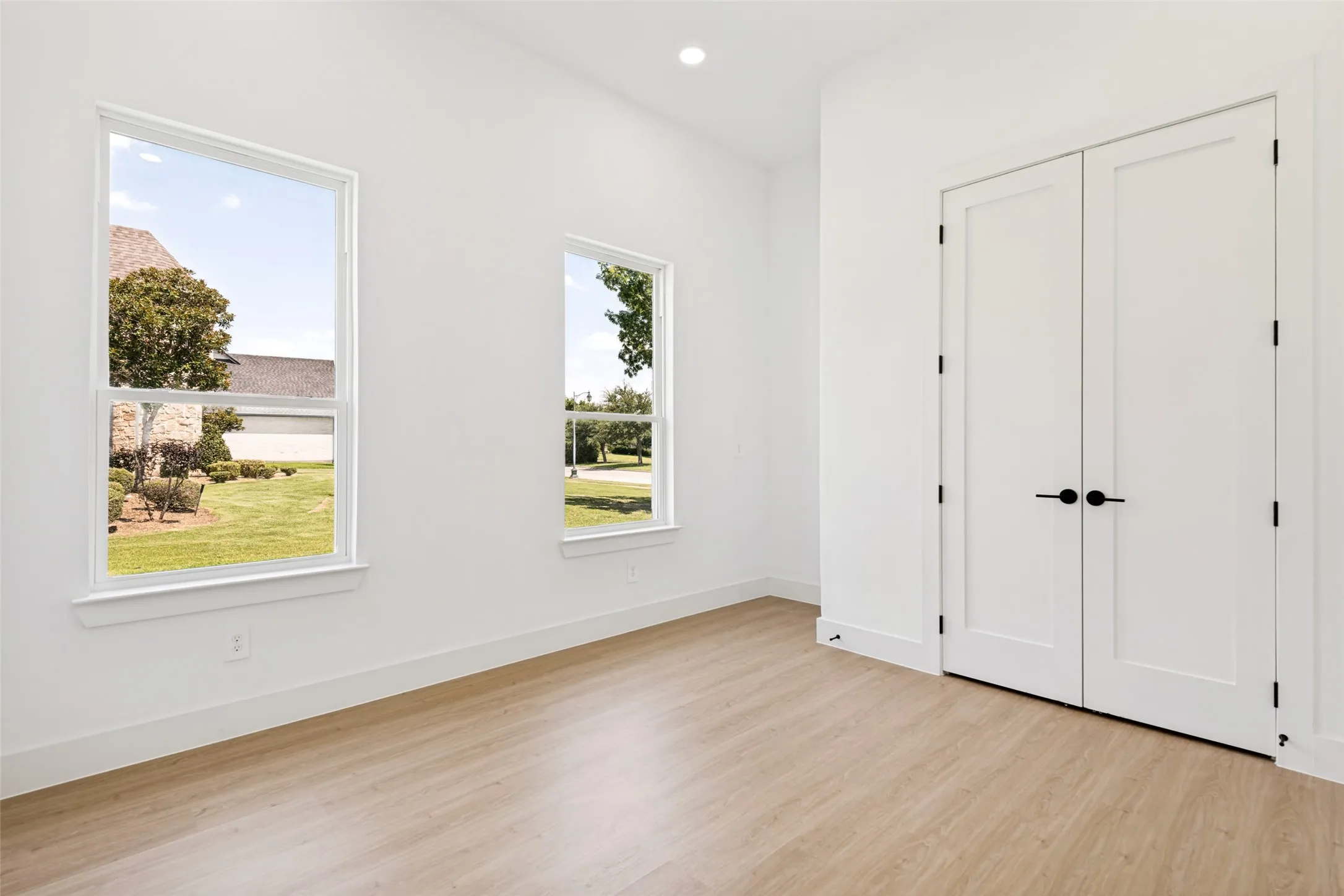 Bright interior space with wood-finish flooring and dual panel doors featuring matte black hardware