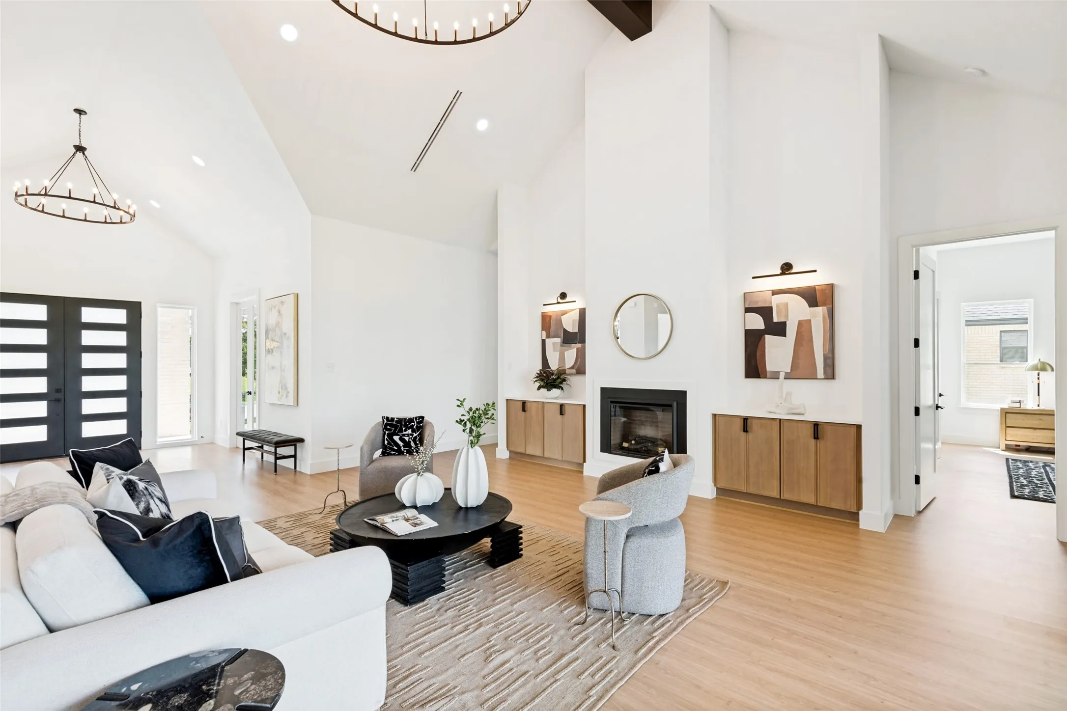 Spacious living area featuring vaulted ceilings, wood-finish flooring, and a modern fireplace with built-in cabinetry