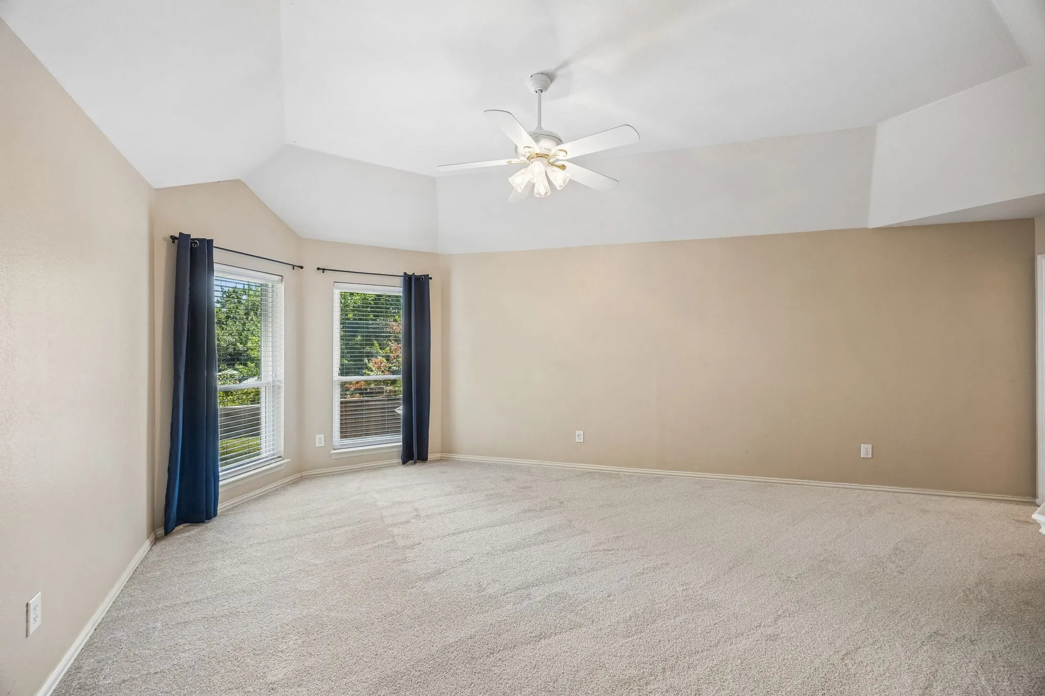 Another view of the gameroom with nice sized windows, ceiling fan, new carpet and high ceiling.