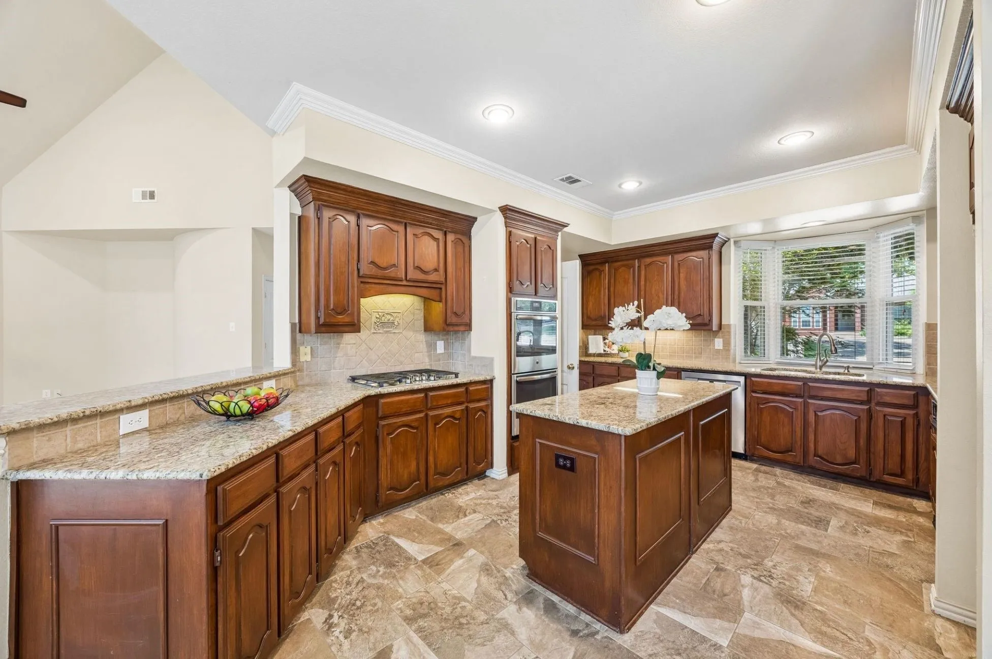 This view of the kitchen shows the amazing prep space you have as well as the open flow to the family room. This peninsula would be a great place for snacks for evenings in or entertaining. The kitchen boasts a five burner gas cooktop as well as double ovens (one is convection.