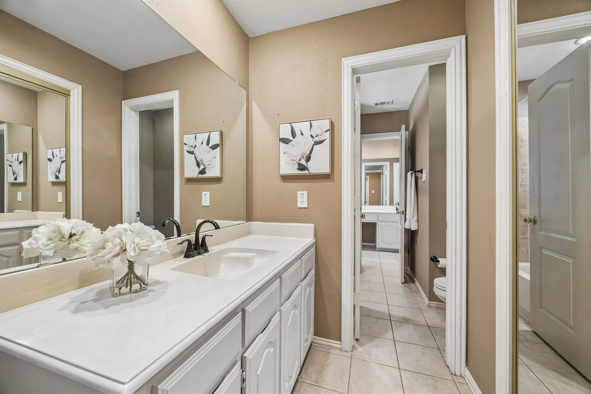 First side of the jack and jill bathroom. This room offers nice sized vanity with storage, oil rubbed bronze fixture and a closet. The bathtub shower and water closet are between the two vanity areas.
