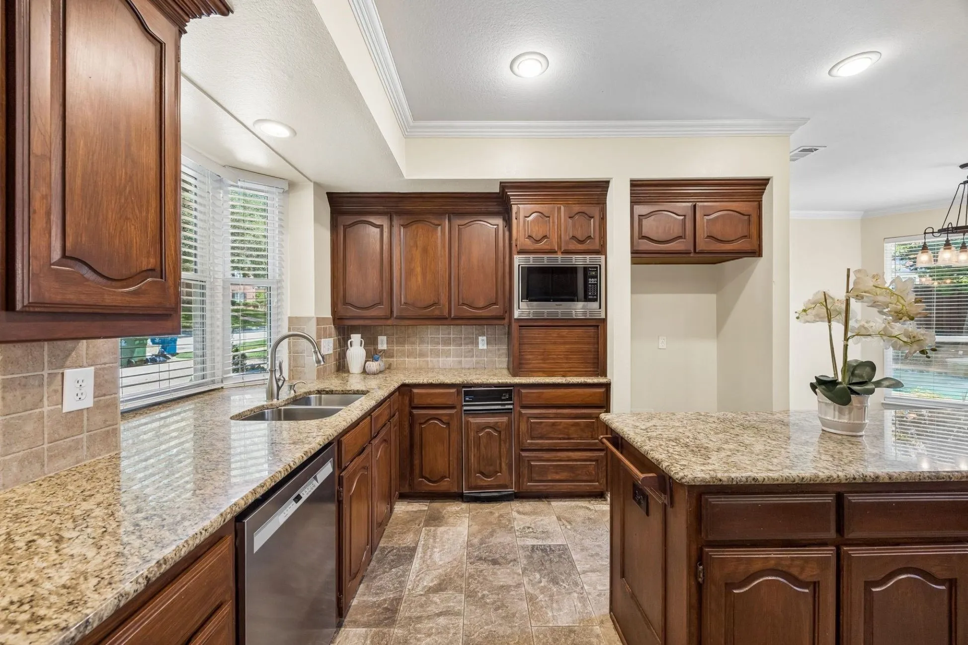 The spacious kitchen offers expansive storage and counter space with 42 in cabinets, larger island and appliance garage. Granite countertops and tumbled stone tile backsplash create a striking look with the cherry cabinetry.