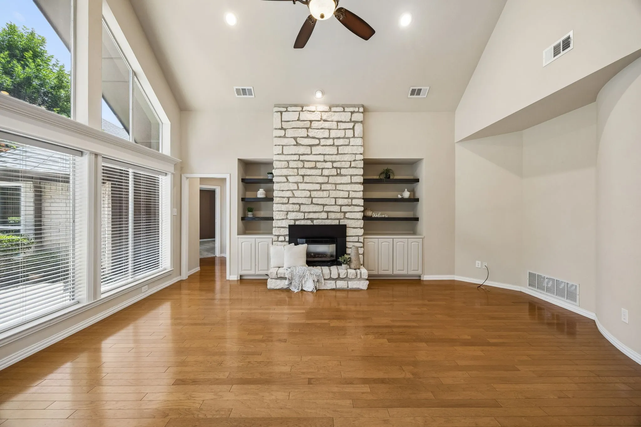 The family room is anchored by a stone fireplace with electric insert. The fireplace is bracketed by built in shelves and storage cabinets. To show the flow of the home the primary as well as the study are through the doorway shown to the left.