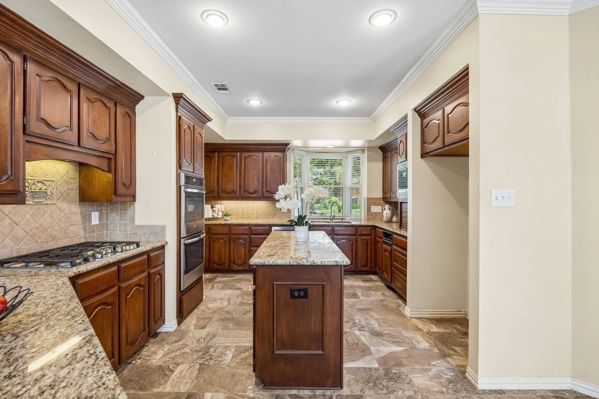Additional features of the kitchen include oversized tile flooring, stainless appliances, dishwasher (2024), pantry, recessed lighting and crown moulding.