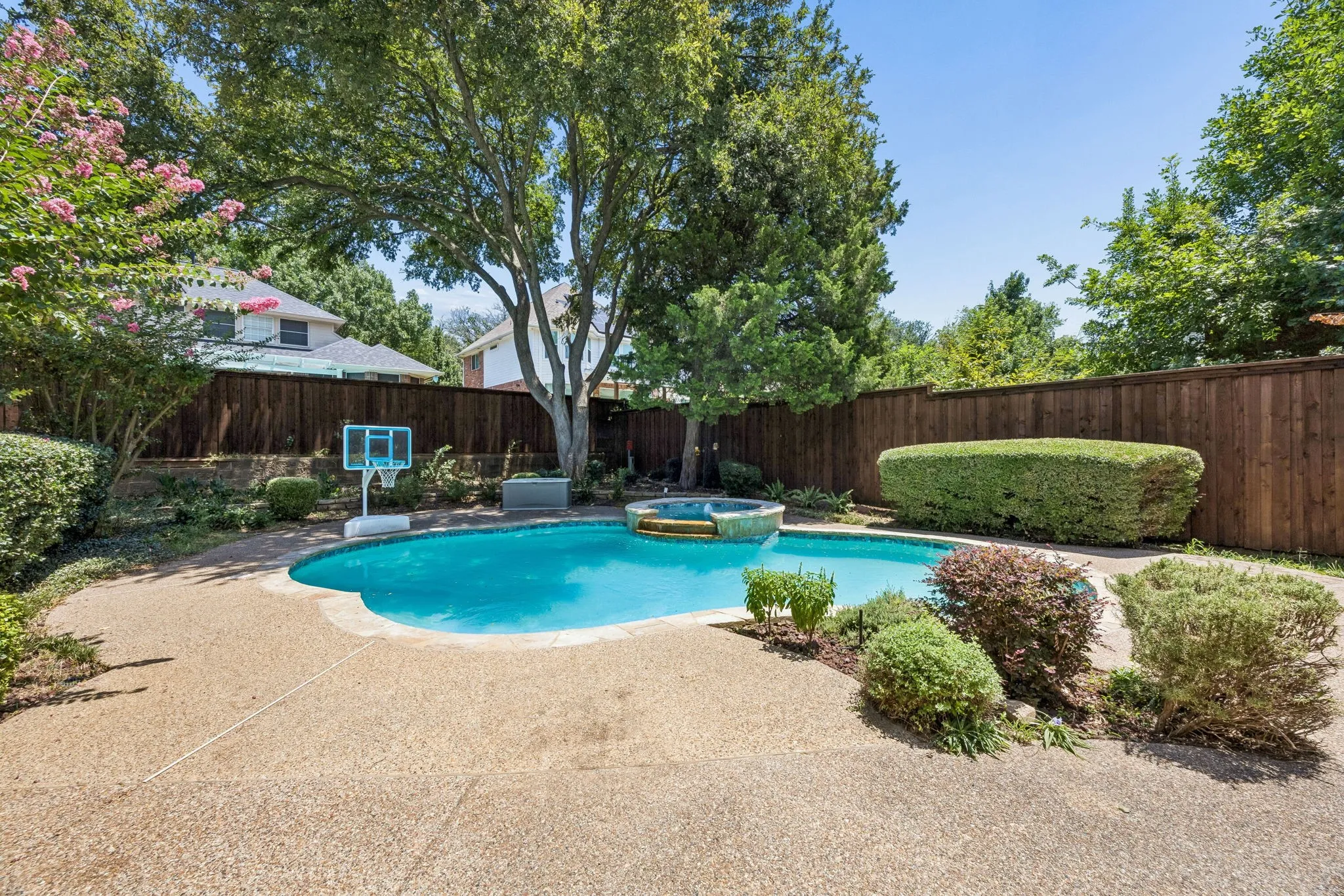 Looking from the backyard toward the pool. Landscaped beds with mature trees and shrubs create a delightful space.