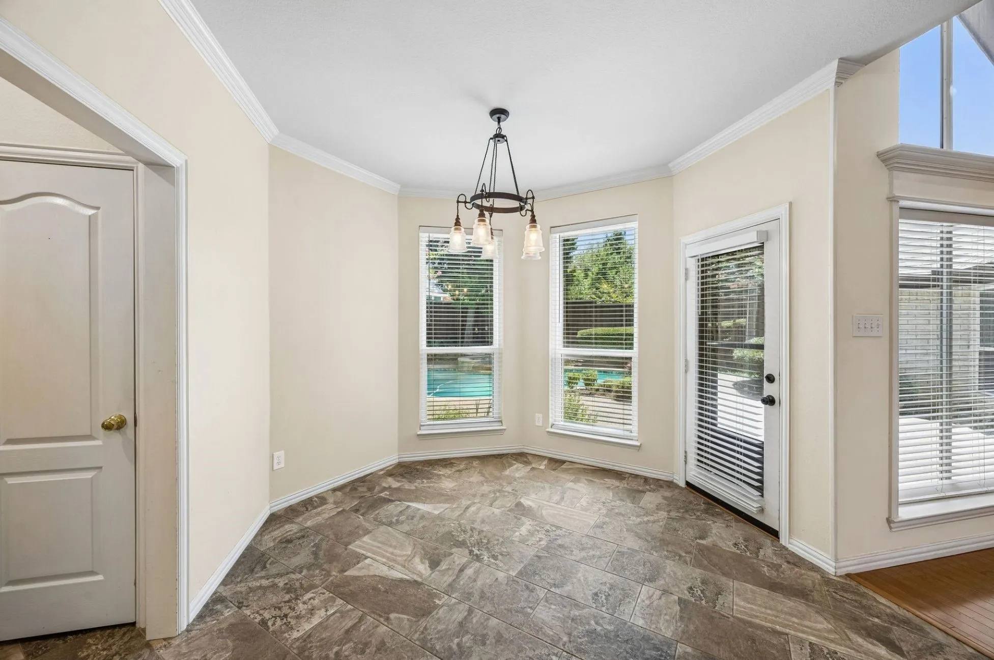 The casual dining area off the kitchen offers views of the pool as well as access to the backyard, oversized tile flooring, oil rubbed bronze light fixture and crown moulding.