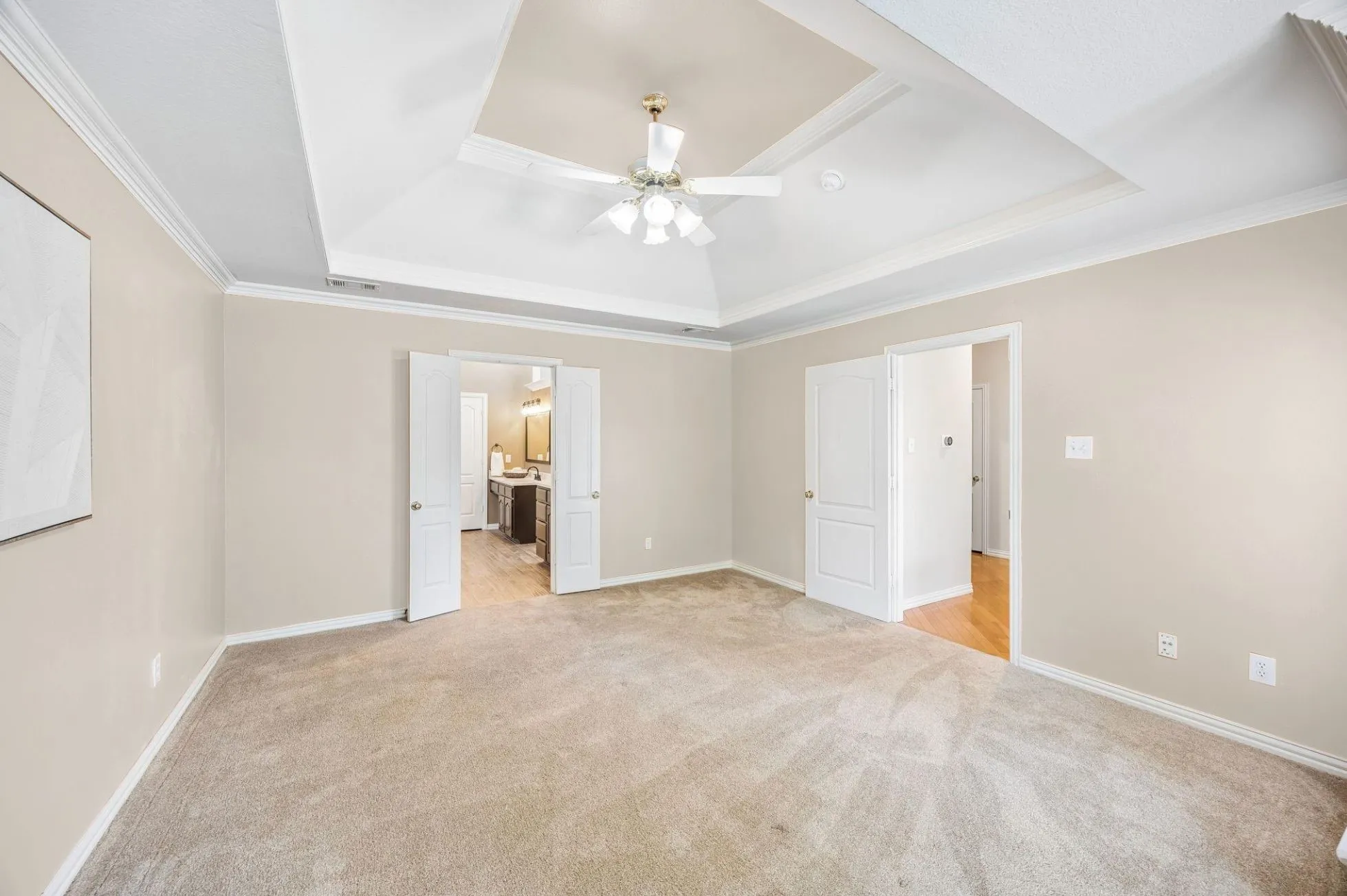 Features of the room include tray ceiling with double crown moulding, ceiling fan and new plush carpet. The en suite bathroom is through the french doors shown.