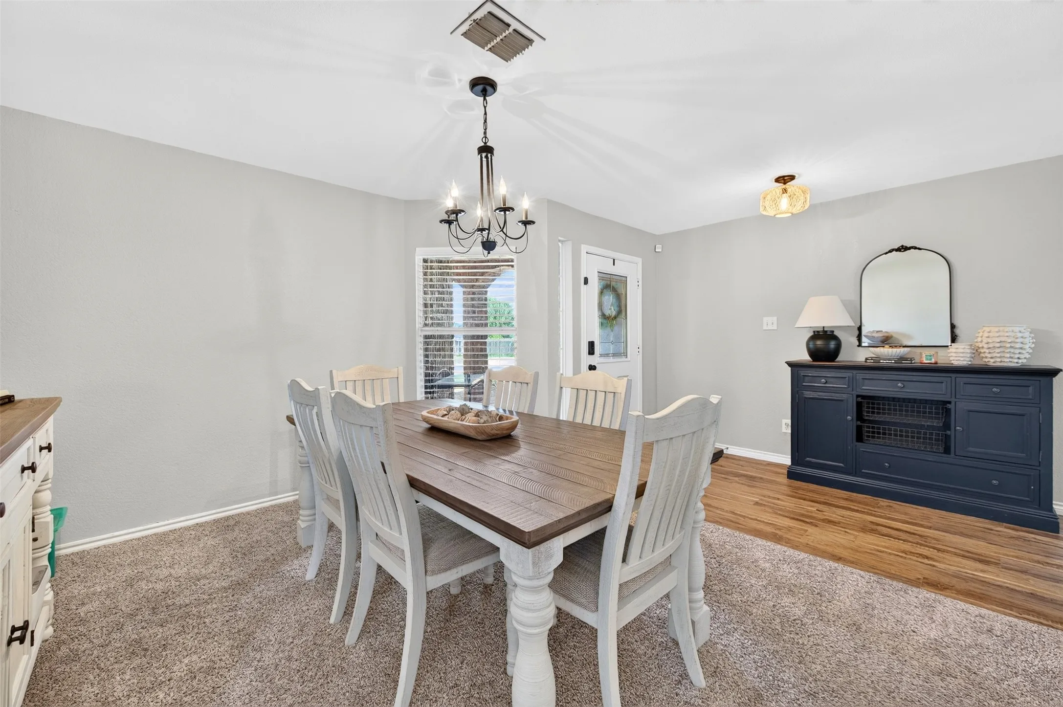 Dining area featuring a modern chandelier, light gray walls, and a window with blinds