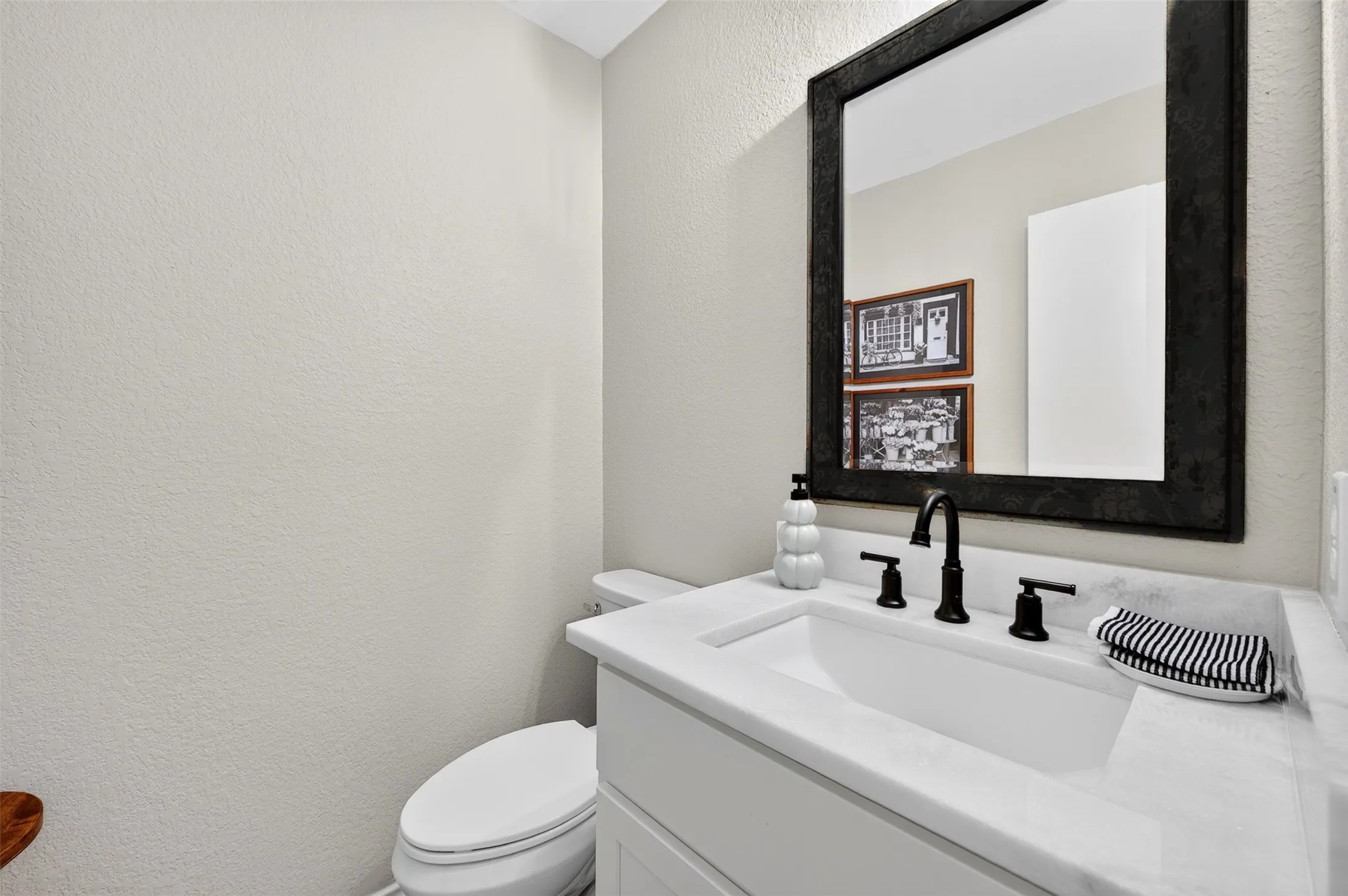 Bathroom vanity featuring a rectangular undermount sink, a white countertop, and matte black faucet fixtures